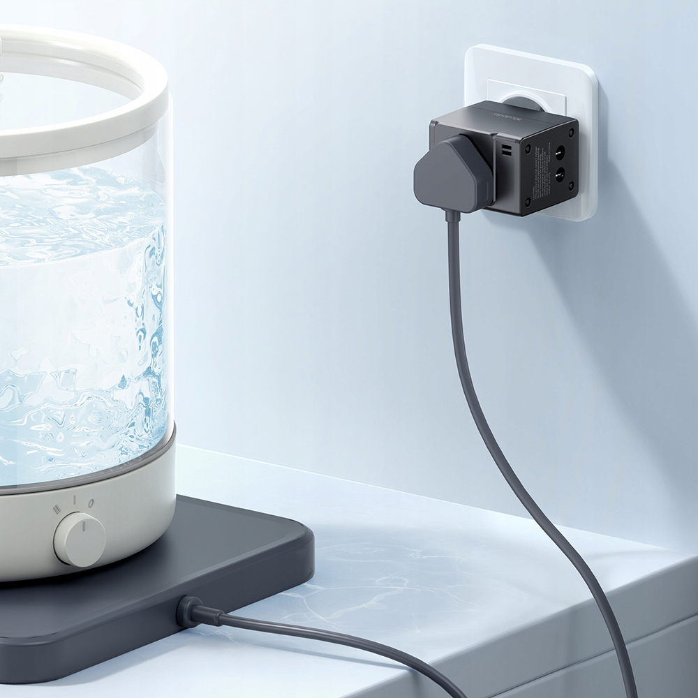 Un adattatore per presa grigio nel muro, collegato a un contenitore d'acqua su un supporto grigio.