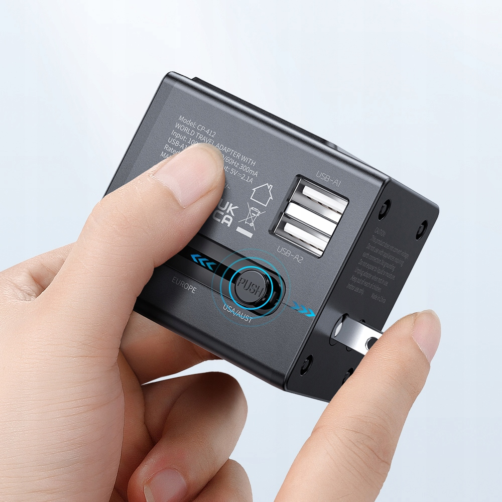 Una mano tiene un adattatore da viaggio nero con porte USB e interruttori.