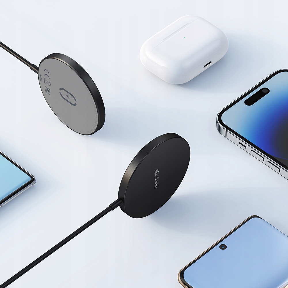 Due caricatori MagSafe neri, auricolari wireless e smartphone su sfondo bianco.