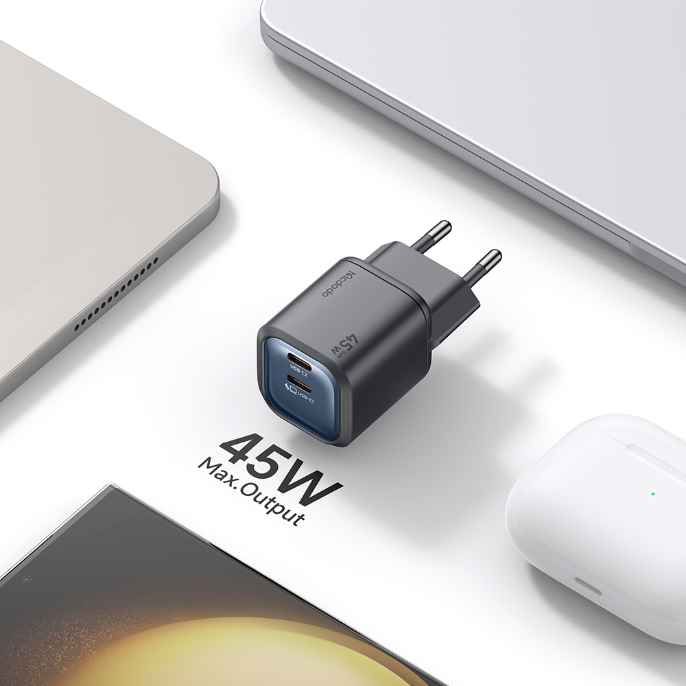 Siyah 45W Mcdodo çift USB-C şarj cihazı beyaz masada elektronik cihazlarla çevrili duruyor.