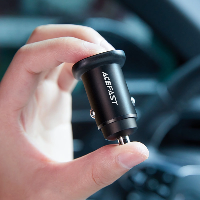 Una mano tiene un caricabatterie per auto nero Acefast davanti all'interno di un'auto.