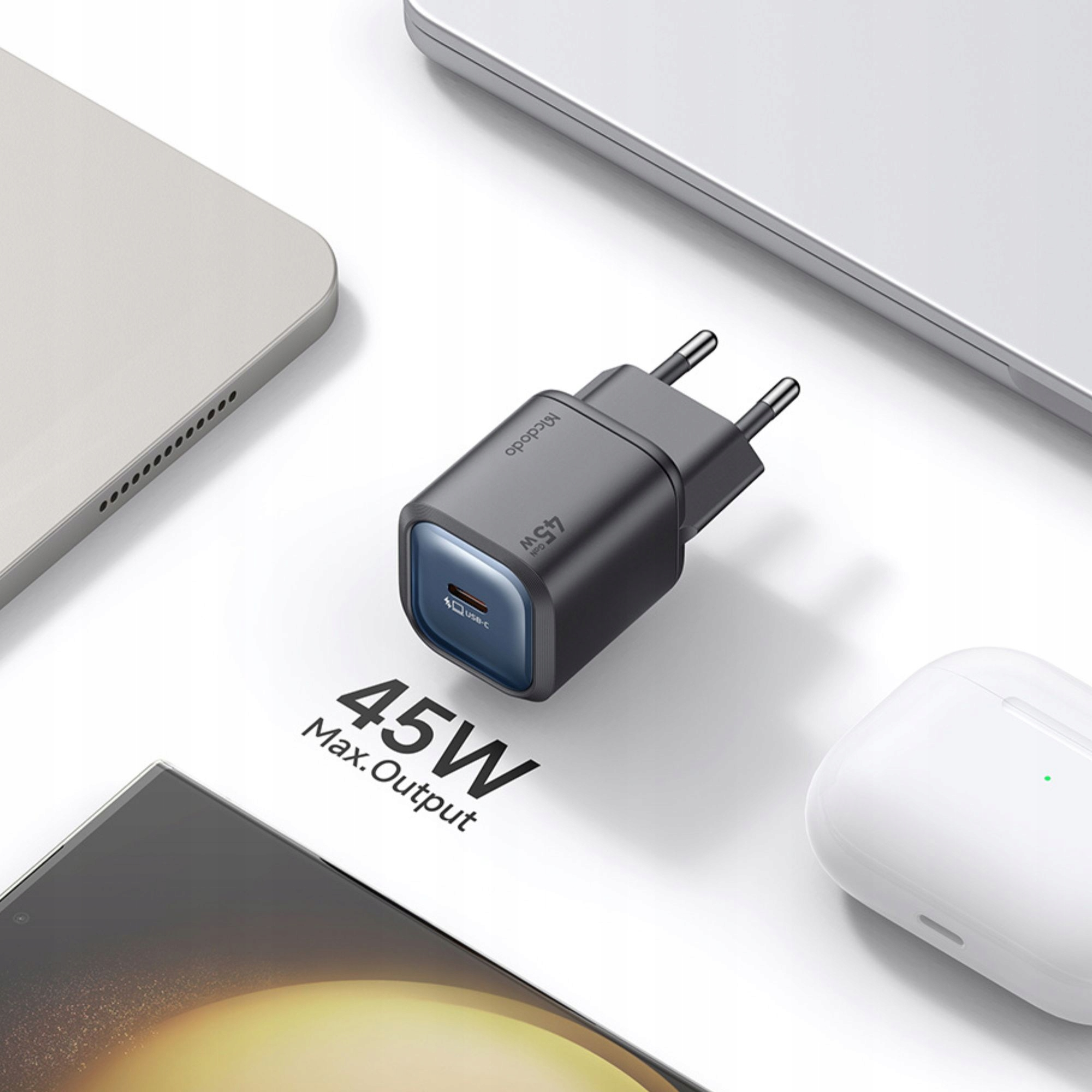 Beyaz bir masada, cihazlarla çevrili siyah bir 45W Mcdodo USB-C şarj cihazı duruyor.