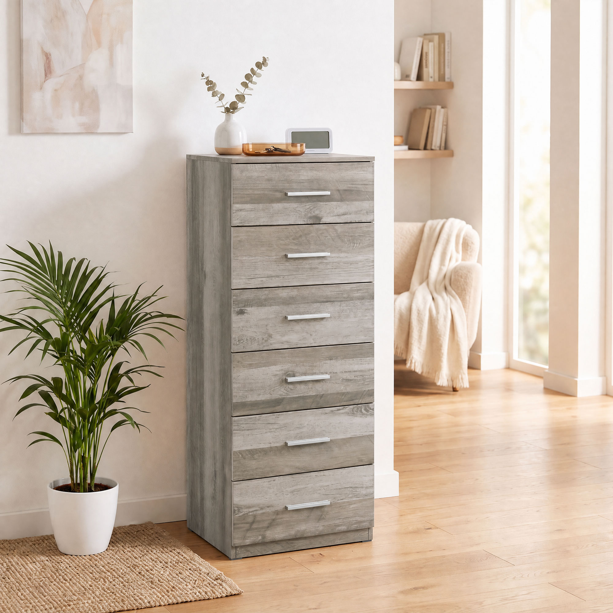 Cómoda alta de madera gris con seis cajones, tiradores plateados, planta en maceta y decoración.