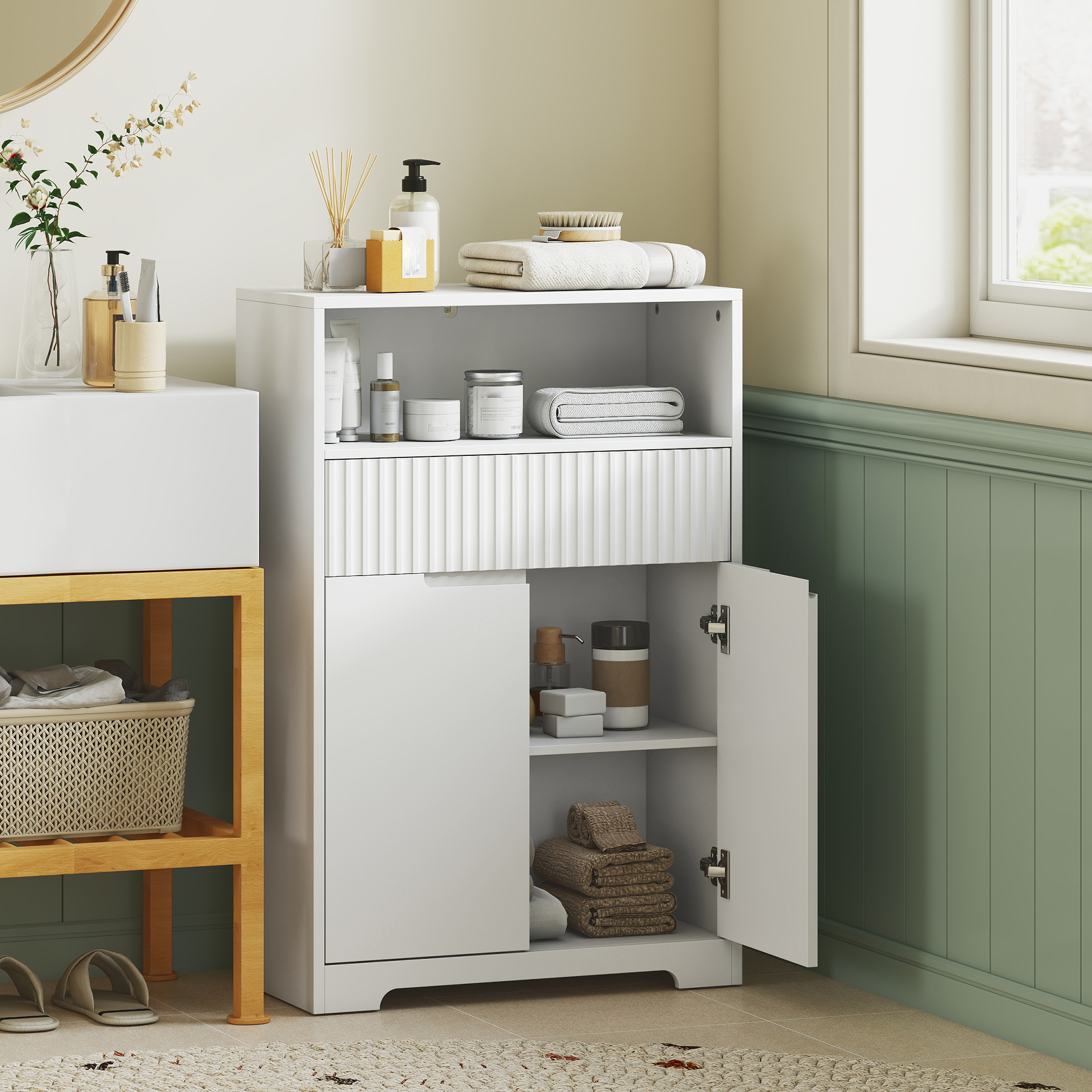 Mueble de baño blanco con balda abierta, cajón y puerta abierta, con toallas y artículos de aseo.