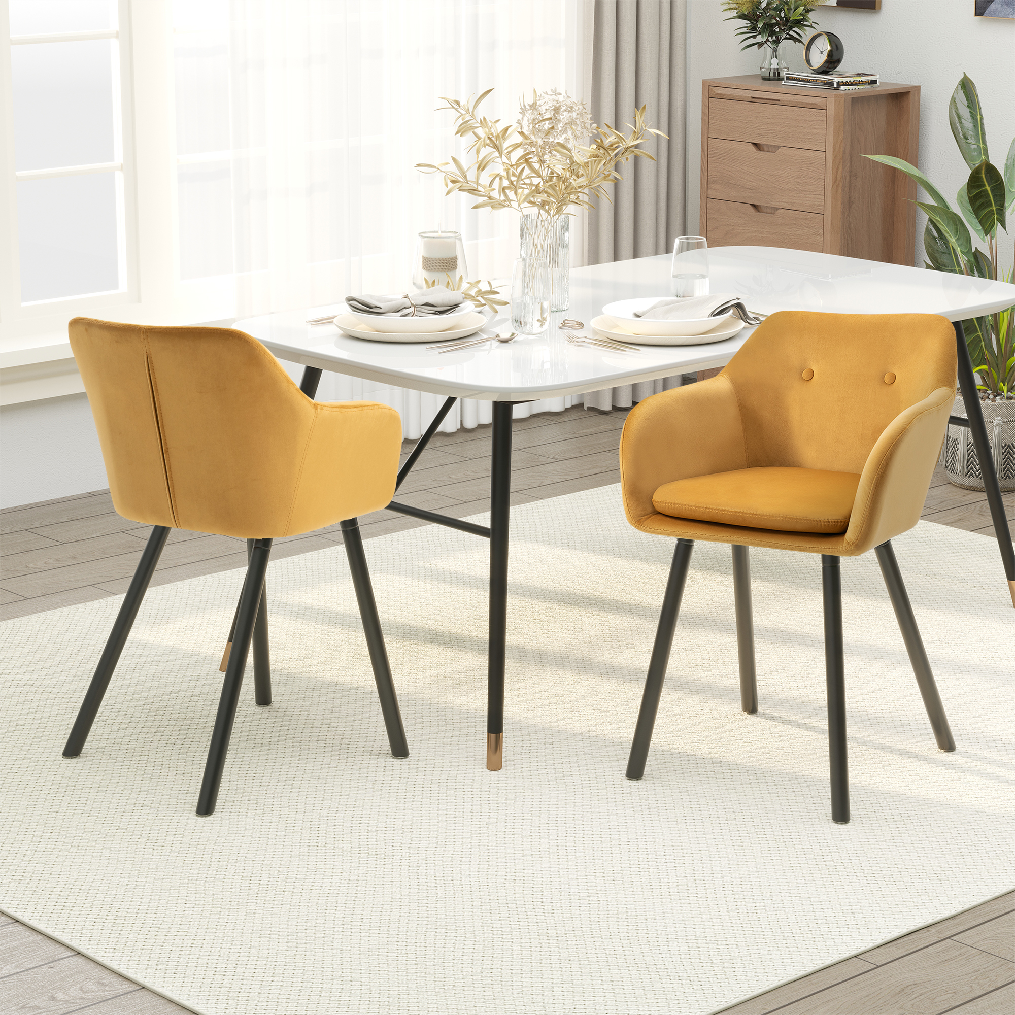 Due sedie in velluto giallo accanto a un tavolo da pranzo bianco su un tappeto chiaro in una sala da pranzo soleggiata.