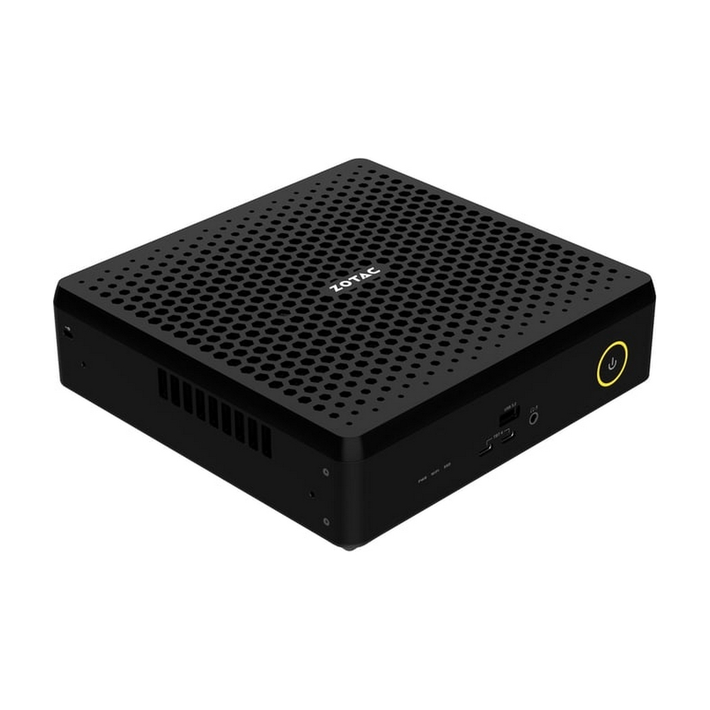 Mini PC Zotac nero con parte superiore perforata e pulsante di accensione giallo su sfondo bianco.
