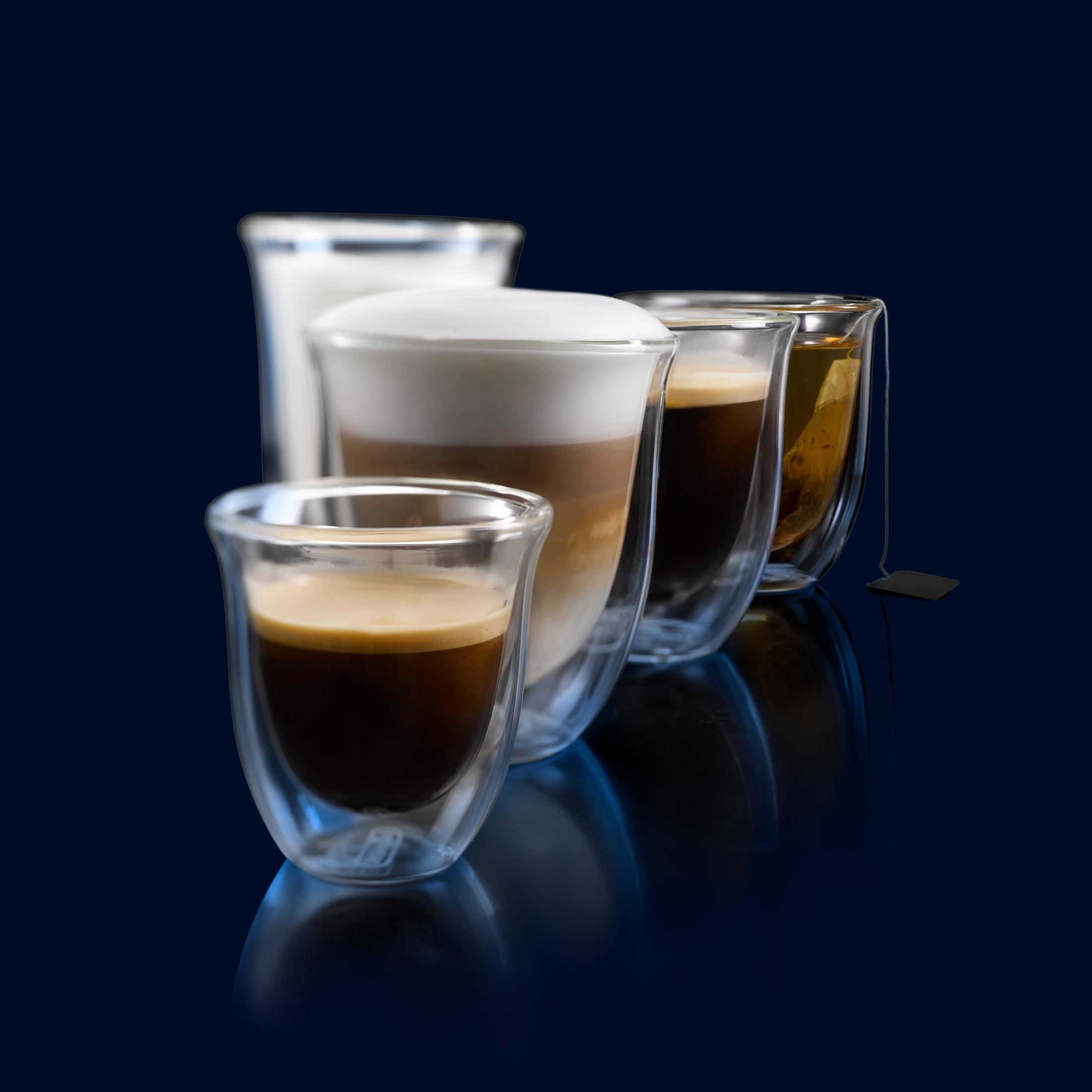 Cinque bicchieri di vetro con caffè, latte e tè con schiuma, disposti in diagonale su una superficie blu.