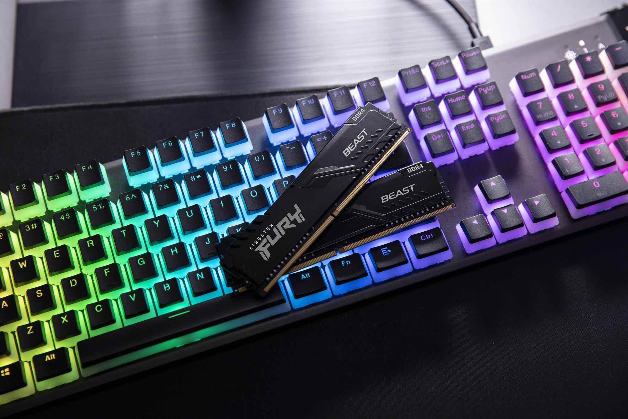 Deux barrettes de RAM Kingston Fury noires reposent sur un clavier lumineux.