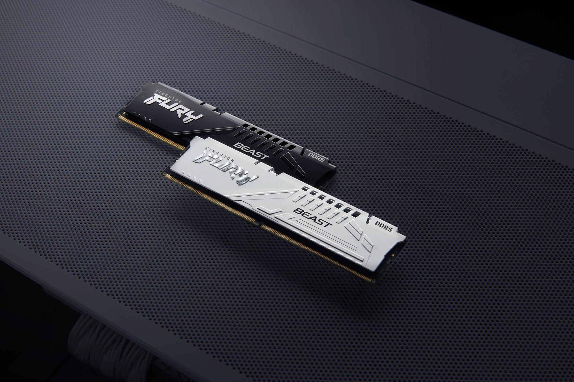 Dwa moduły RAM Kingston FURY Beast DDR5, jeden biały i jeden czarny, na szarym tle.