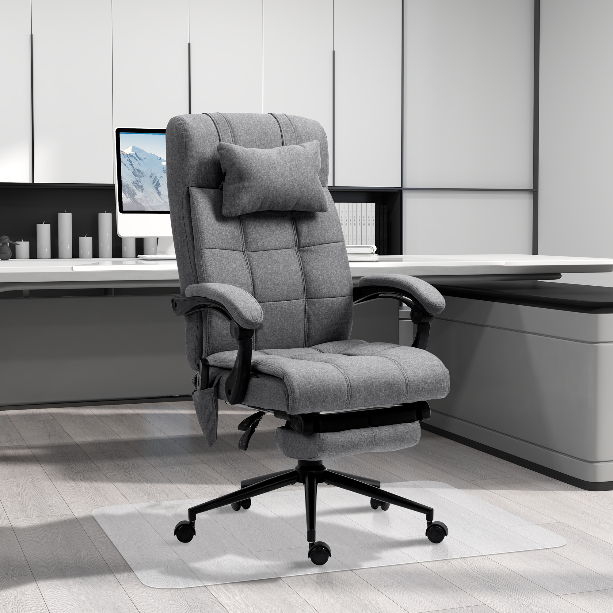 Una silla de oficina ejecutiva gris con cojín para la cabeza frente a un escritorio moderno.