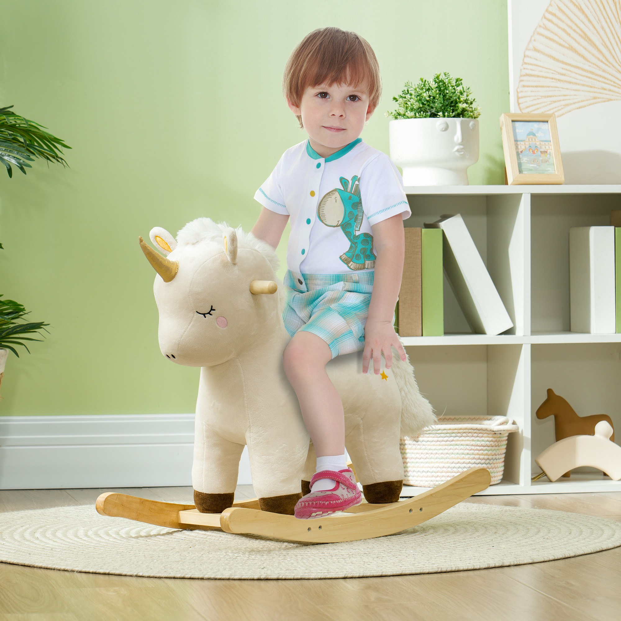 Bambino seduto su un cavallo a dondolo di peluche a forma di unicorno.