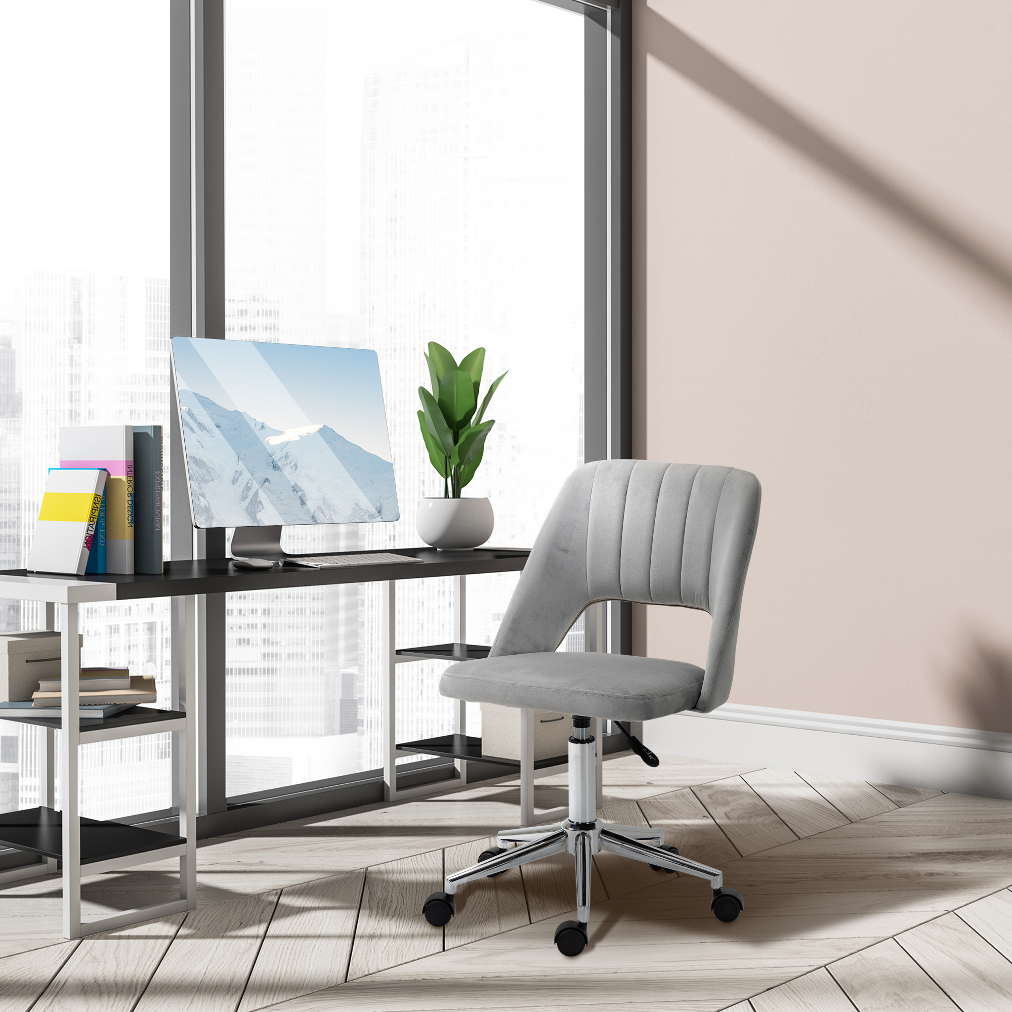 Moderno angolo ufficio con sedia grigia, scrivania con PC, libri e pianta davanti a una grande finestra.