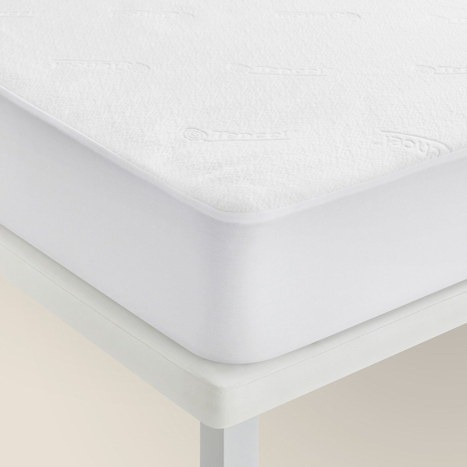 Primer plano de un protector de colchón blanco en una cama con fondo liso.