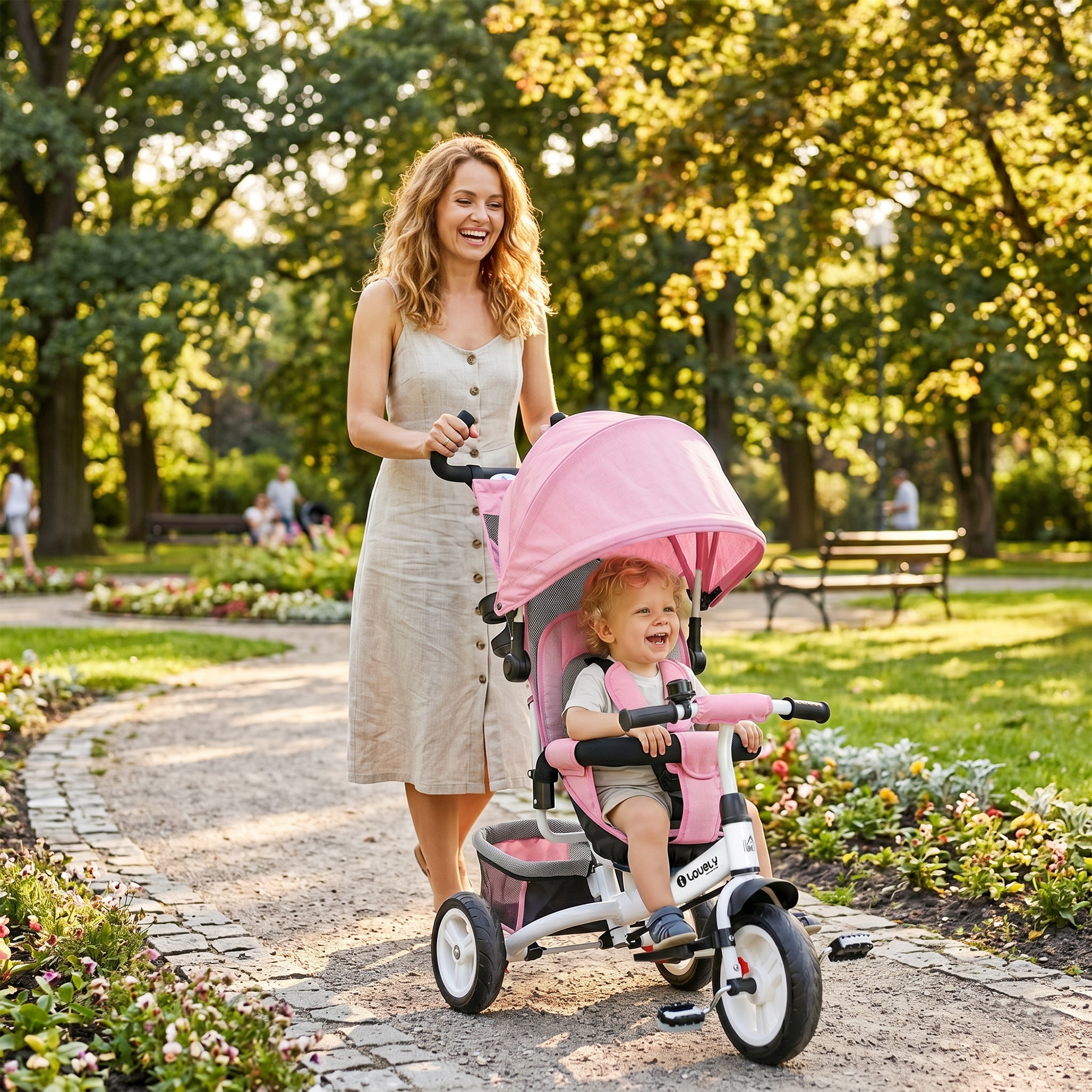 Una madre felice spinge suo figlio su un triciclo rosa lungo un sentiero del parco.