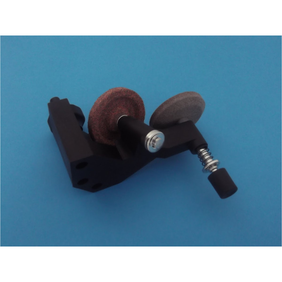 Un supporto per pietra per affilare nero con due mole rotonde e una molla su sfondo blu.