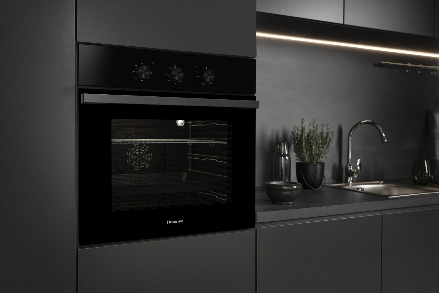 Un moderno forno incassato nero in una cucina scura con lavello, pianta e pensili.