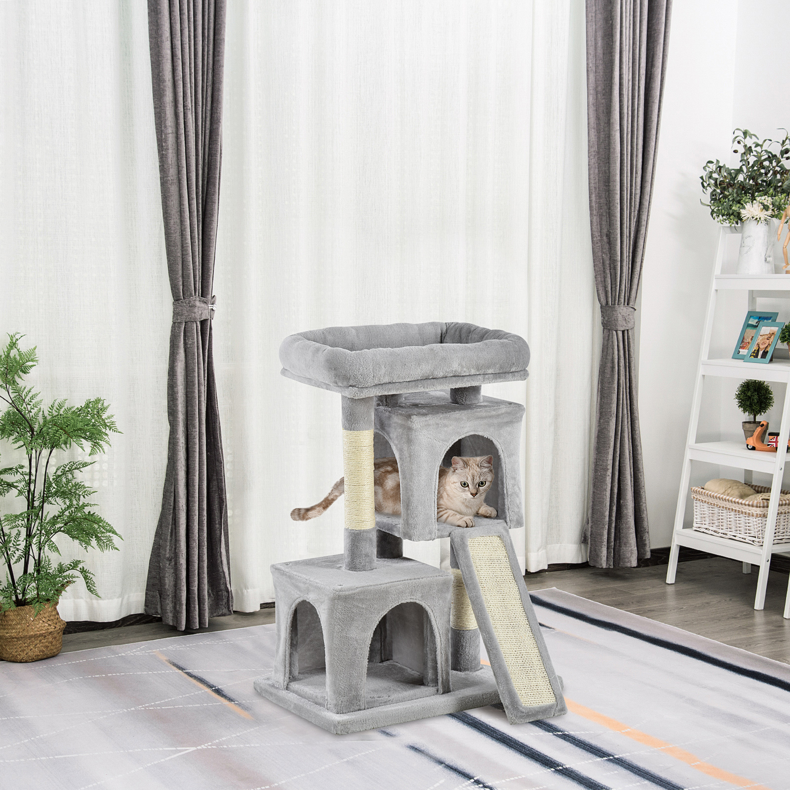 Un albero per gatti grigio con un gattino maculato nella cuccia, su un tappeto fantasia vicino alle tende.
