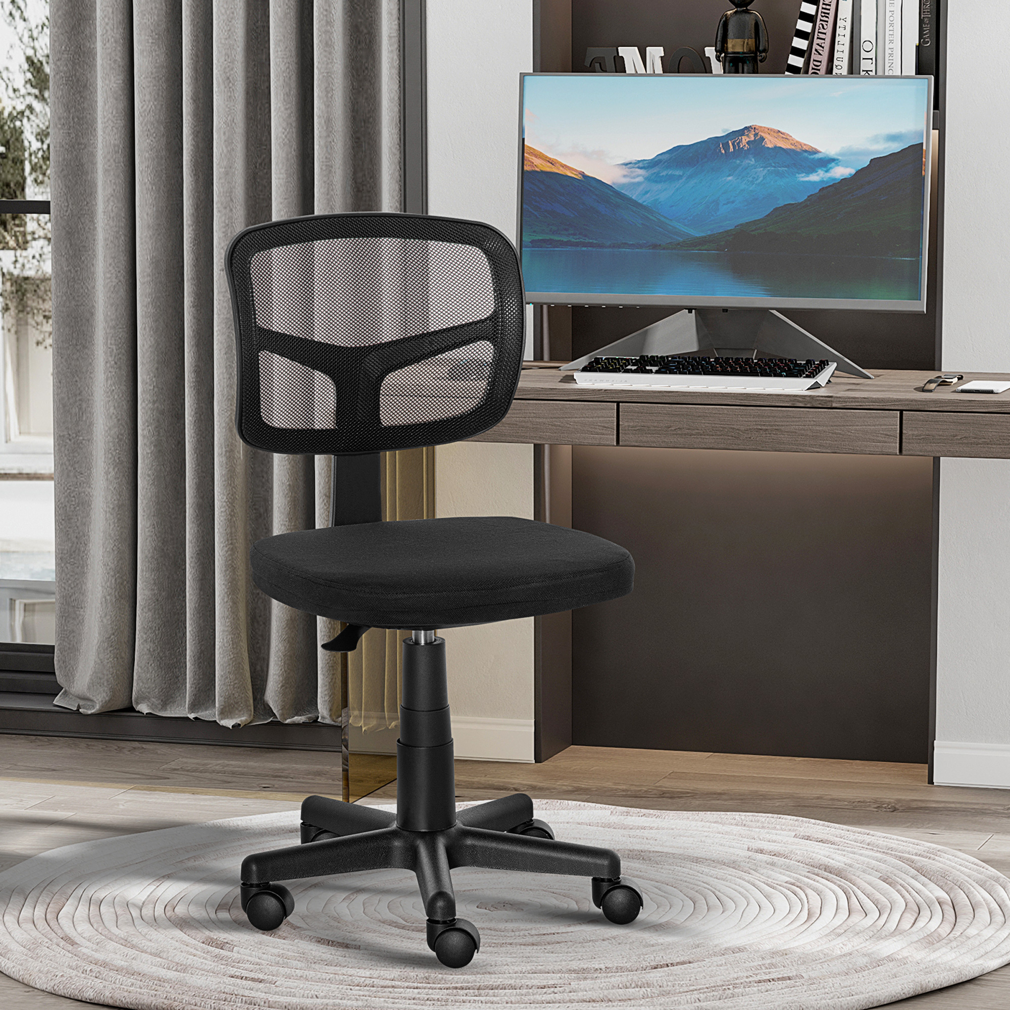 Una sedia da ufficio nera in rete si trova davanti a una scrivania in legno con monitor.