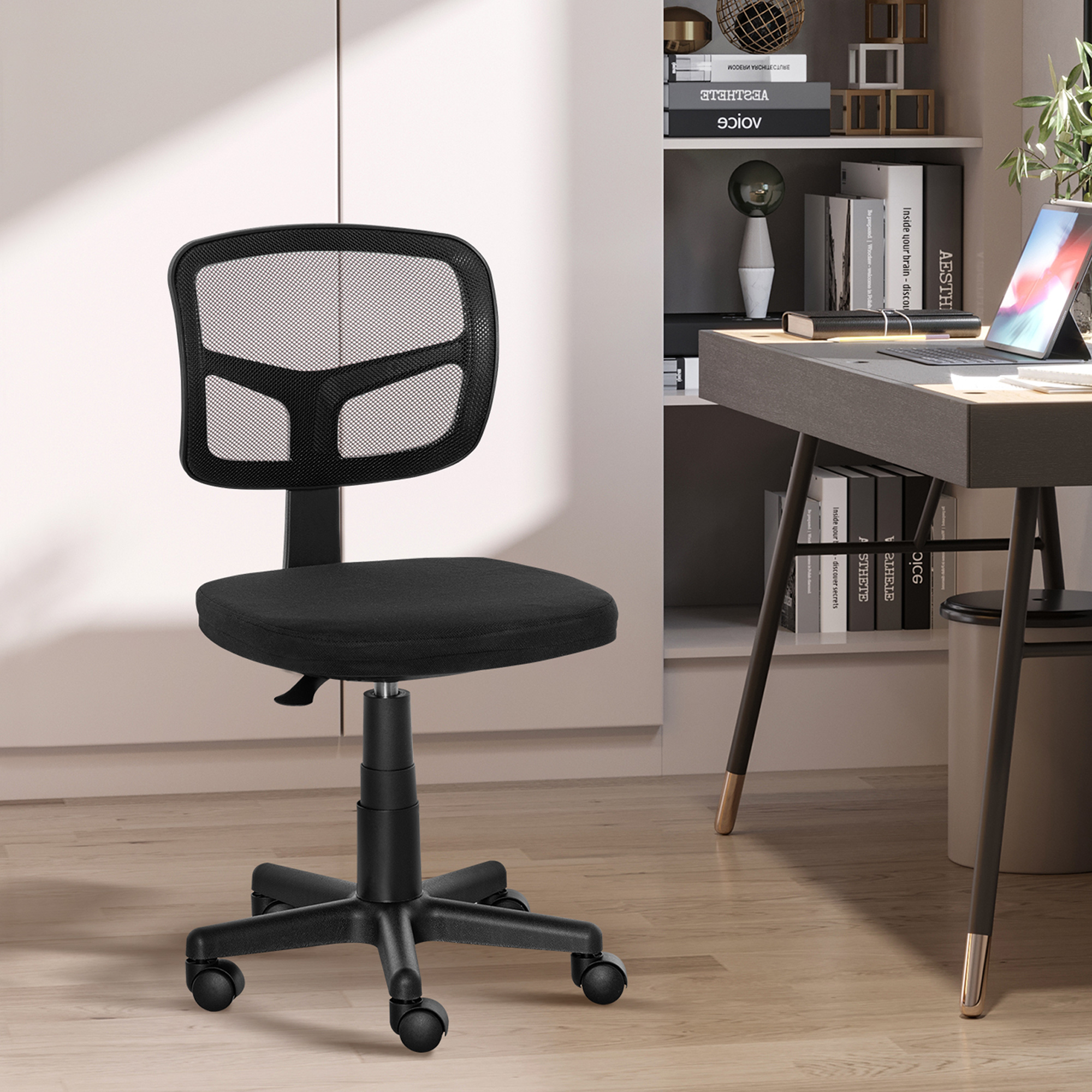 Una sedia da ufficio nera con schienale in rete si trova in un ufficio moderno davanti a una scrivania.