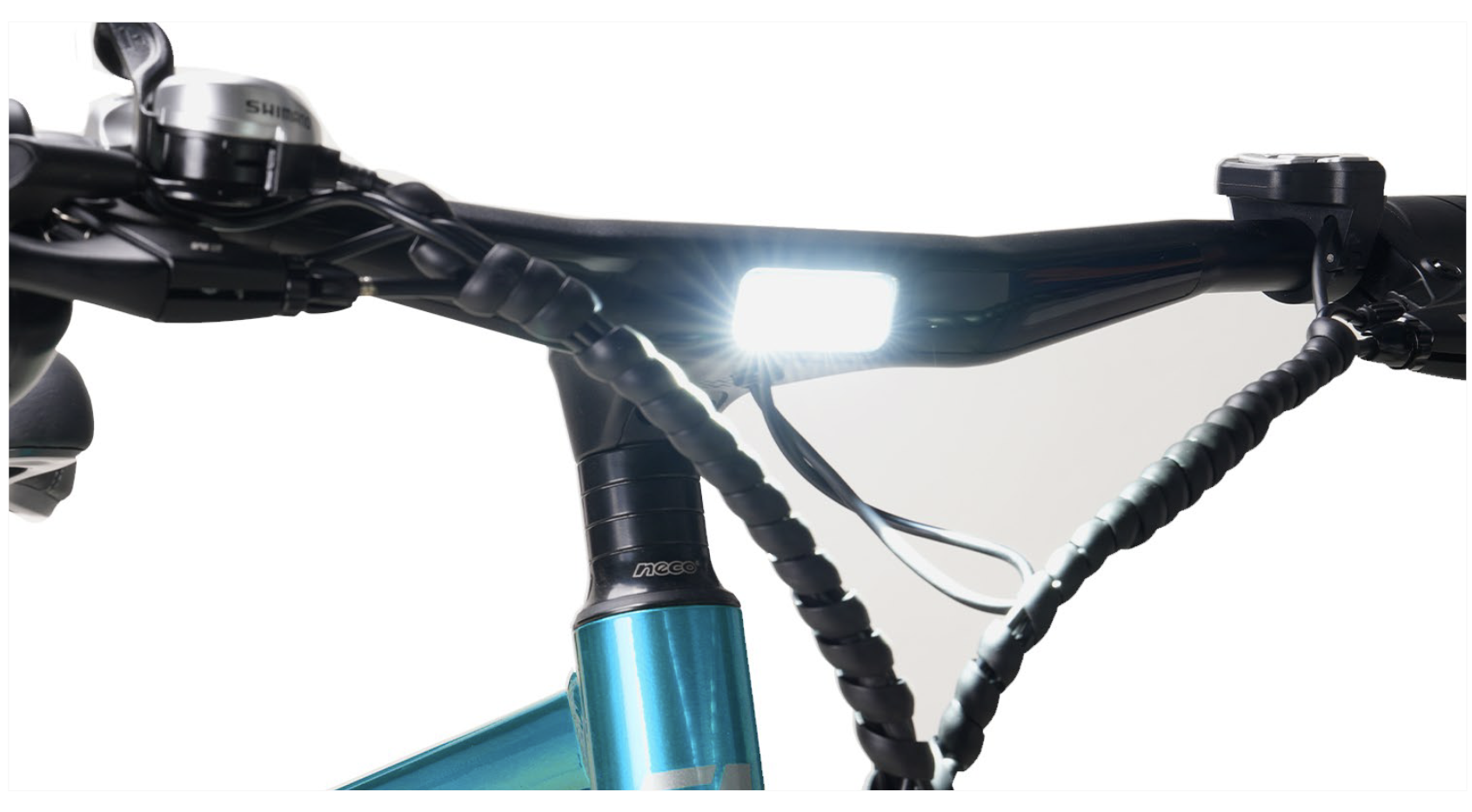 Un manillar de bicicleta iluminado con luz frontal integrada y manetas de freno cableadas en un cuadro azul.