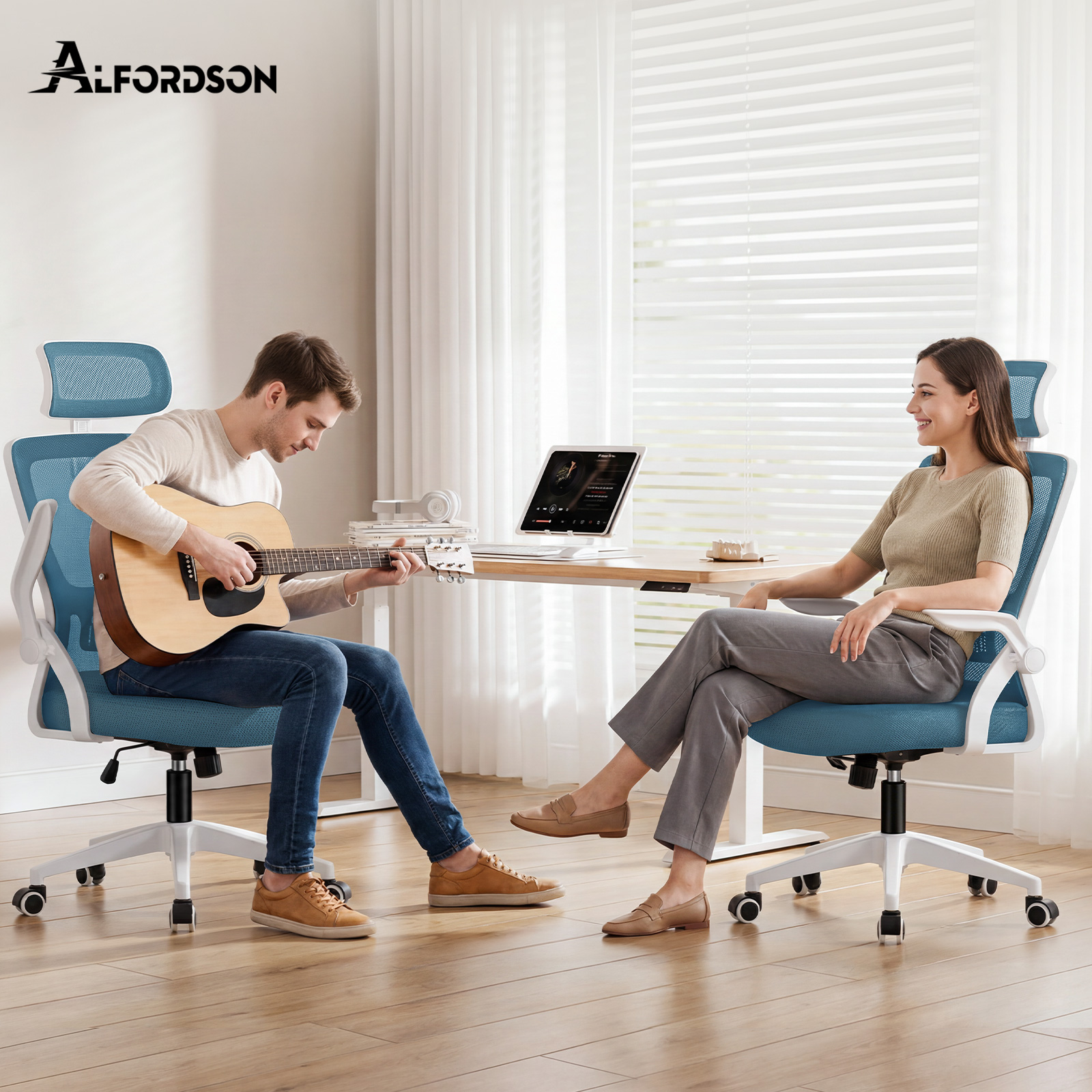 Ein Mann spielt Akustikgitarre und sitzt auf einem blauen Stuhl; eine Frau sitzt auf einem anderen blauen Stuhl.