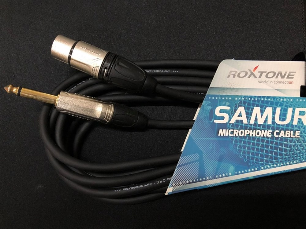 Karanlık bir yüzey üzerinde XLR ve jack fişli bir Roxtone Samurai mikrofon kablosu.