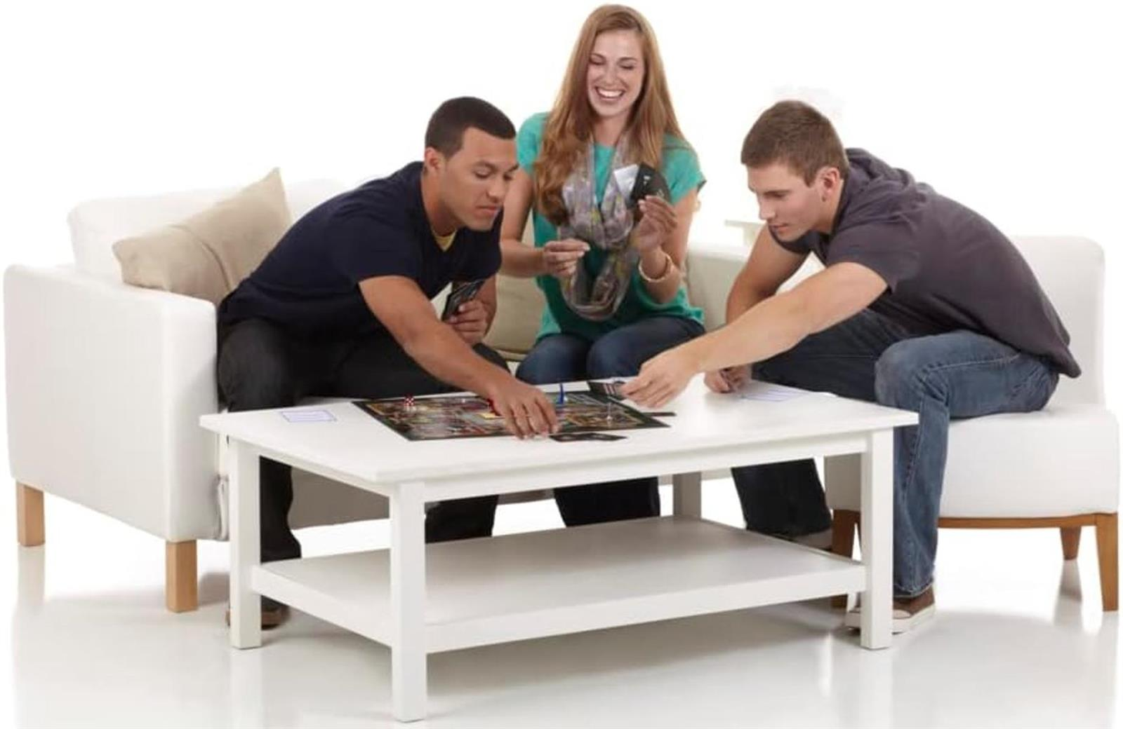Drei junge Erwachsene sitzen auf weißen Sofas und spielen gemeinsam Brettspiele an einem weißen Couchtisch.