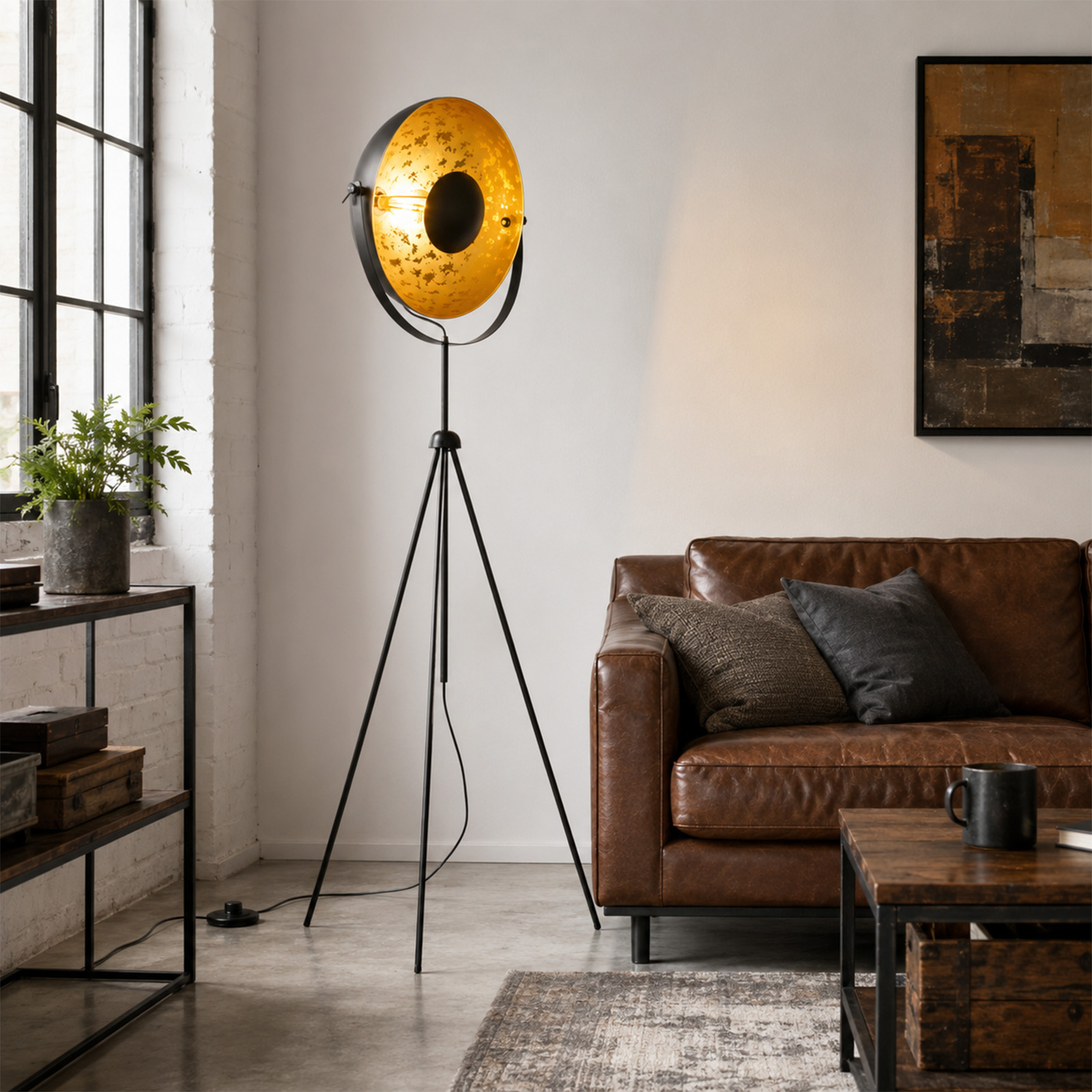 Una lámpara de pie con trípode negro e interior dorado se encuentra en una sala de estar moderna.