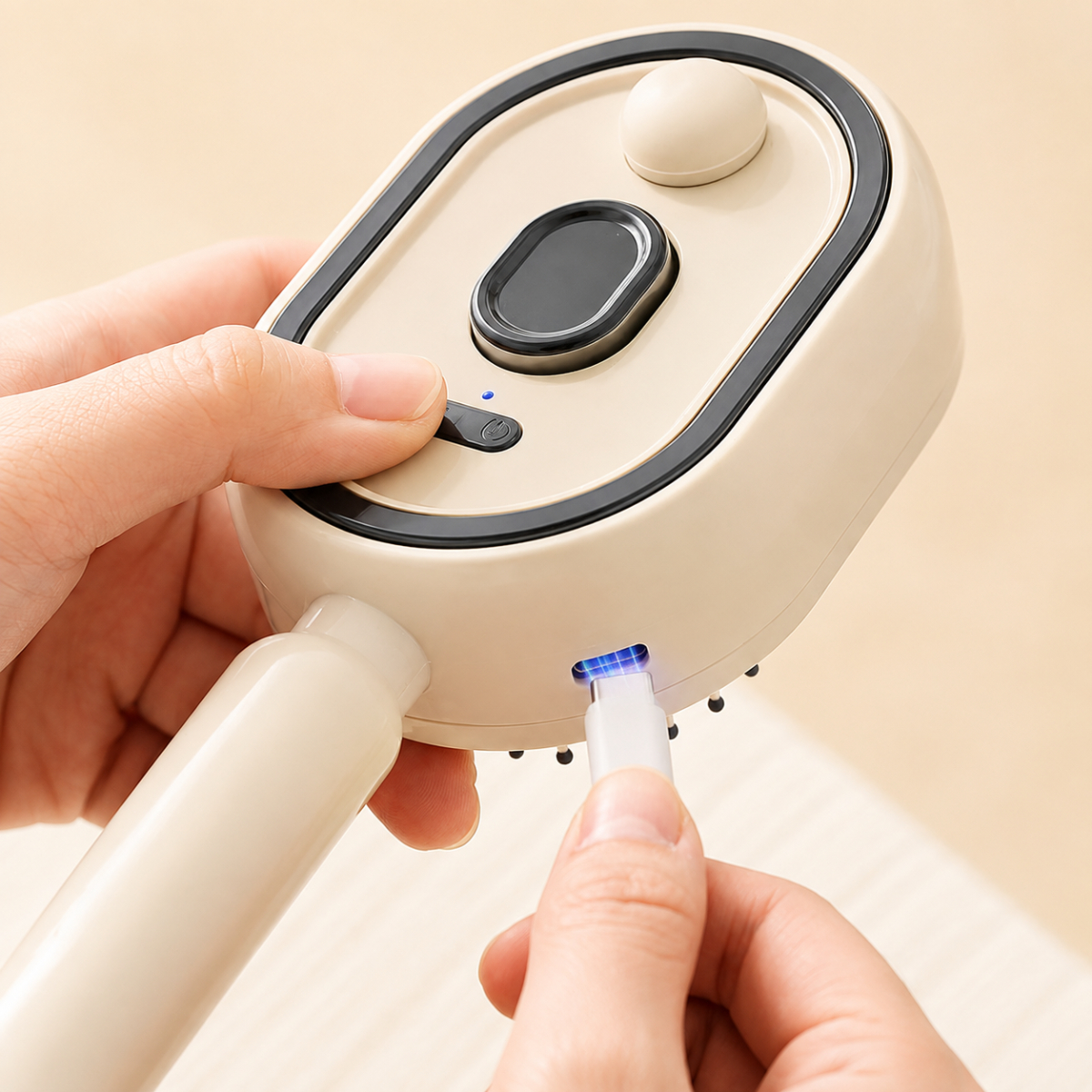 Una mano conecta un cable USB a un cepillo de pelo eléctrico color crema con luz de carga azul.