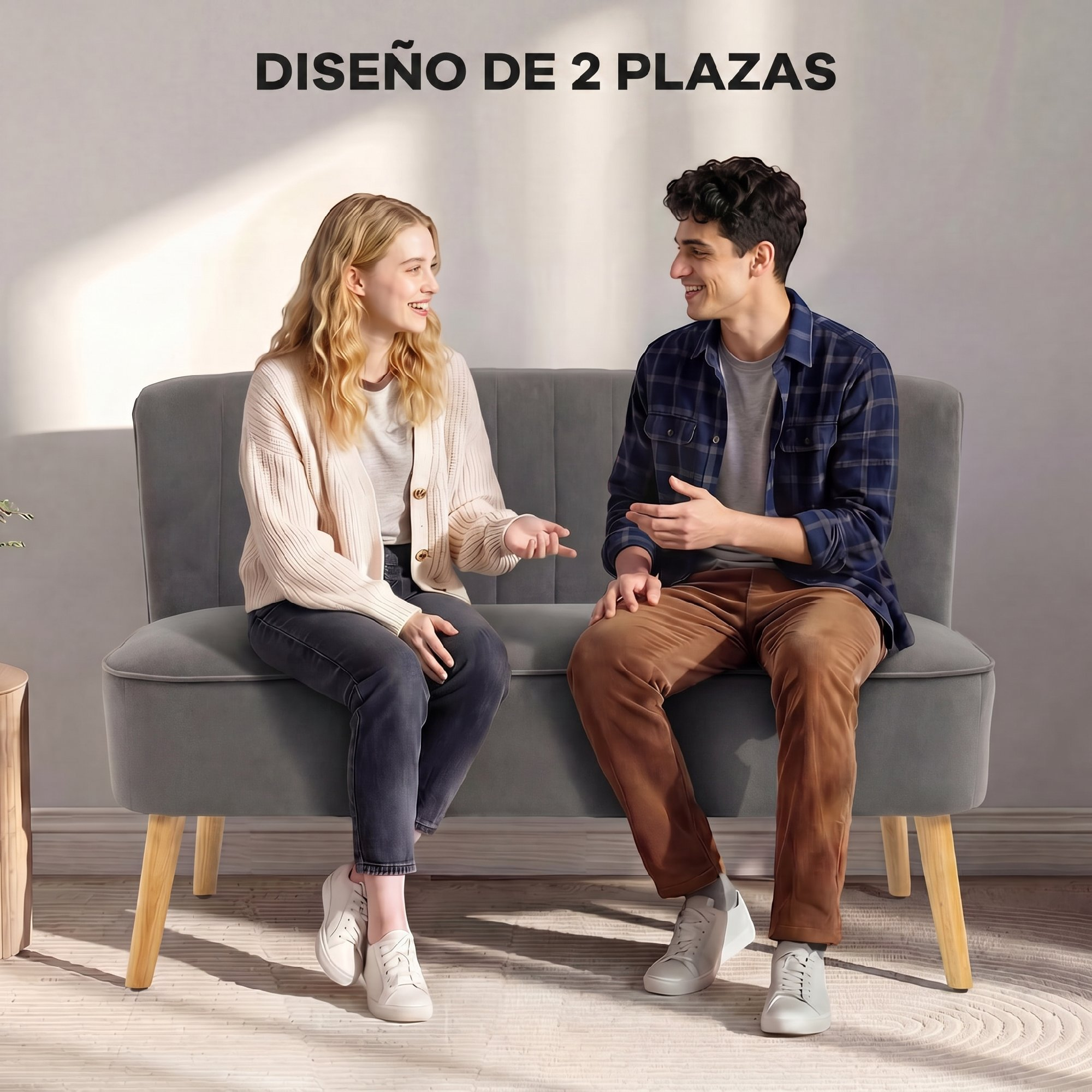 Una joven pareja está sentada en un sofá gris conversando en una habitación luminosa.
