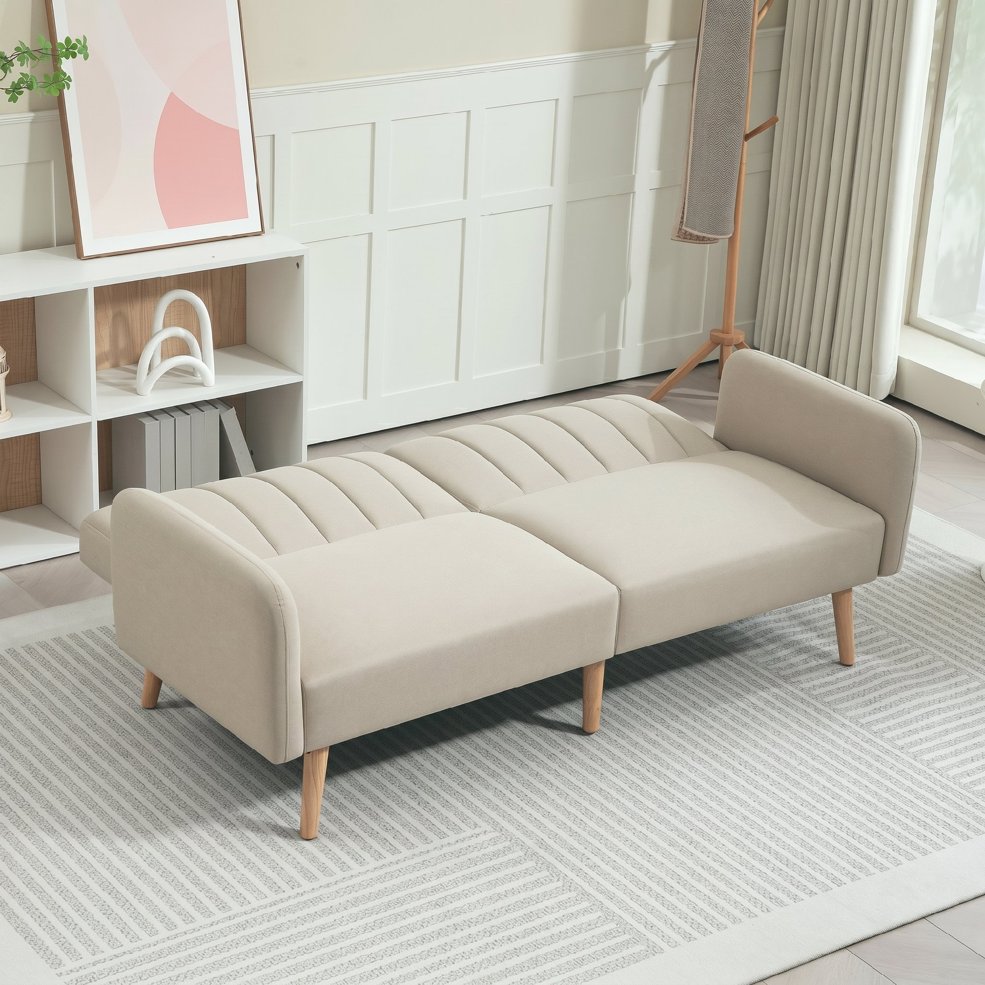 Un sofá futón beige sobre una alfombra estampada en una sala de estar moderna y luminosa con estante y cortinas.