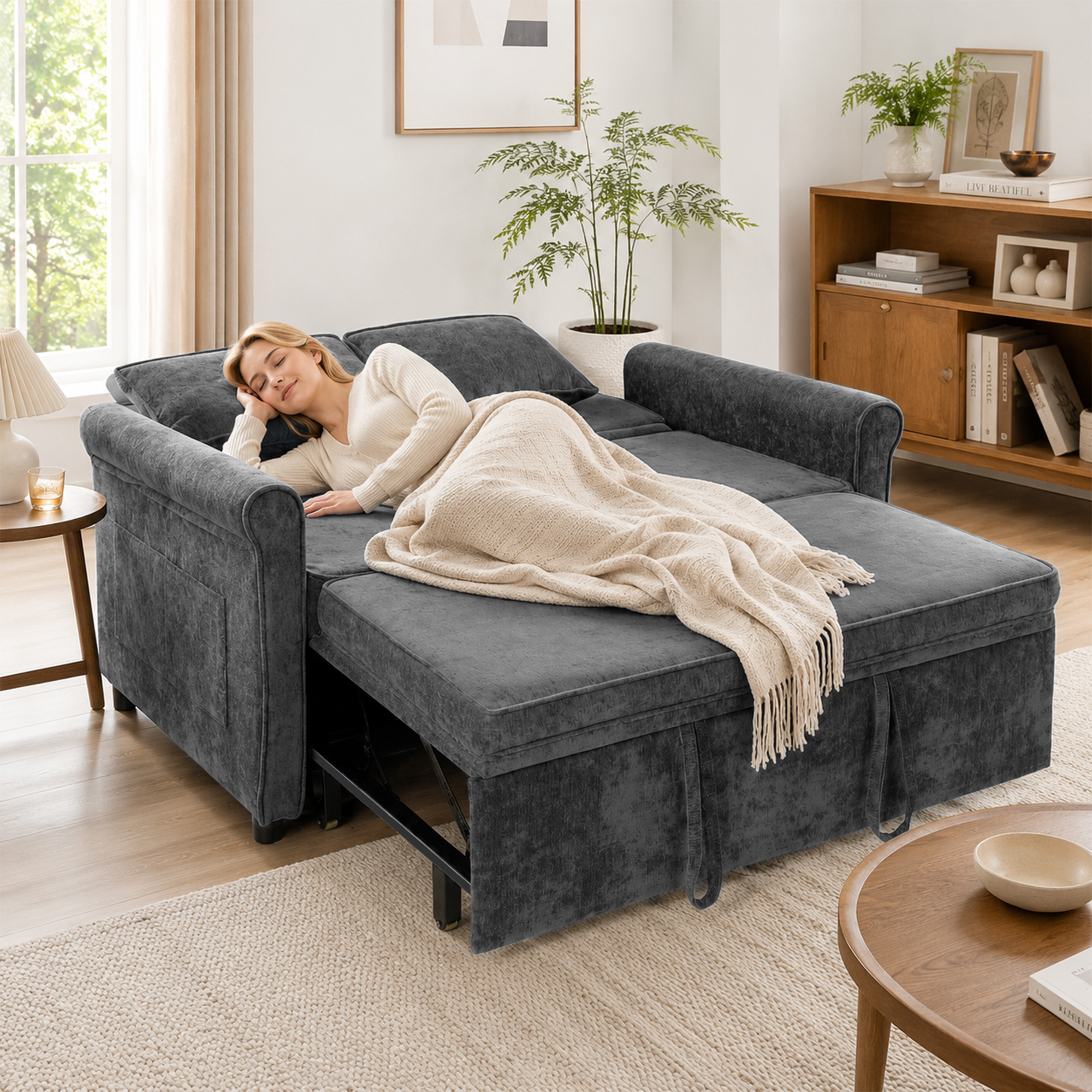 Una mujer rubia duerme plácidamente en un sofá cama gris oscuro desplegado cubierto con una manta.