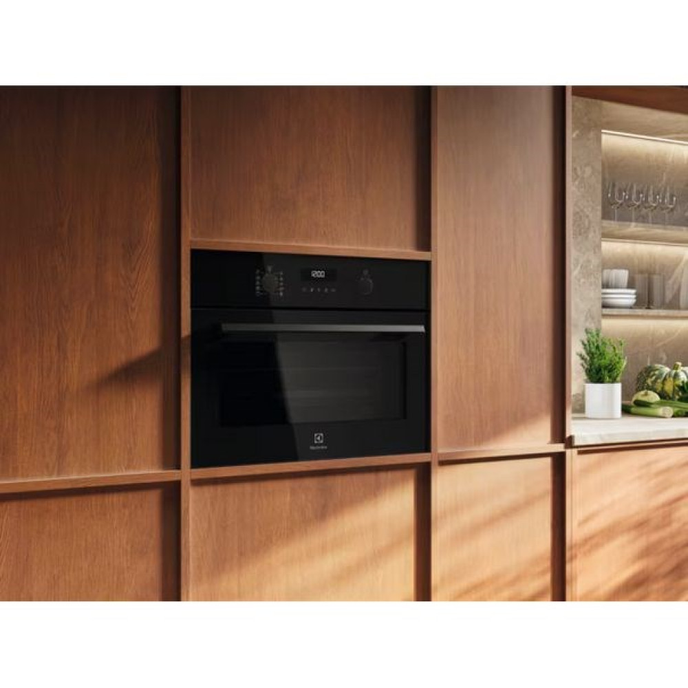 Un forno da incasso nero è installato in mobili da cucina in legno.