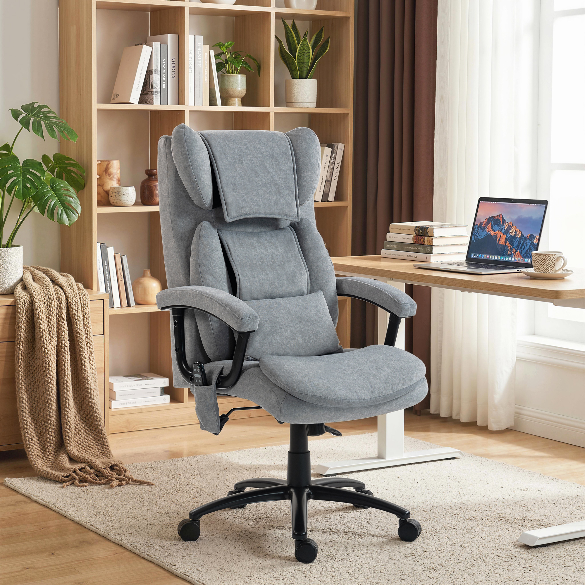 Una silla de oficina gris frente a un escritorio con una computadora y una estantería.