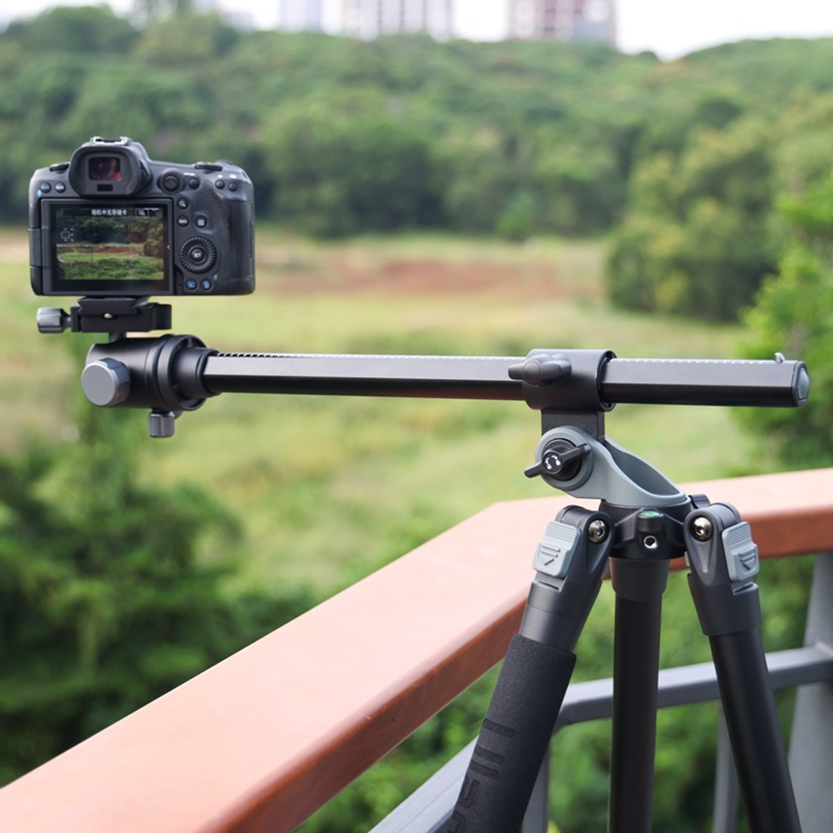 A black camera mounted on an extendable tripod arm against a green natural background.