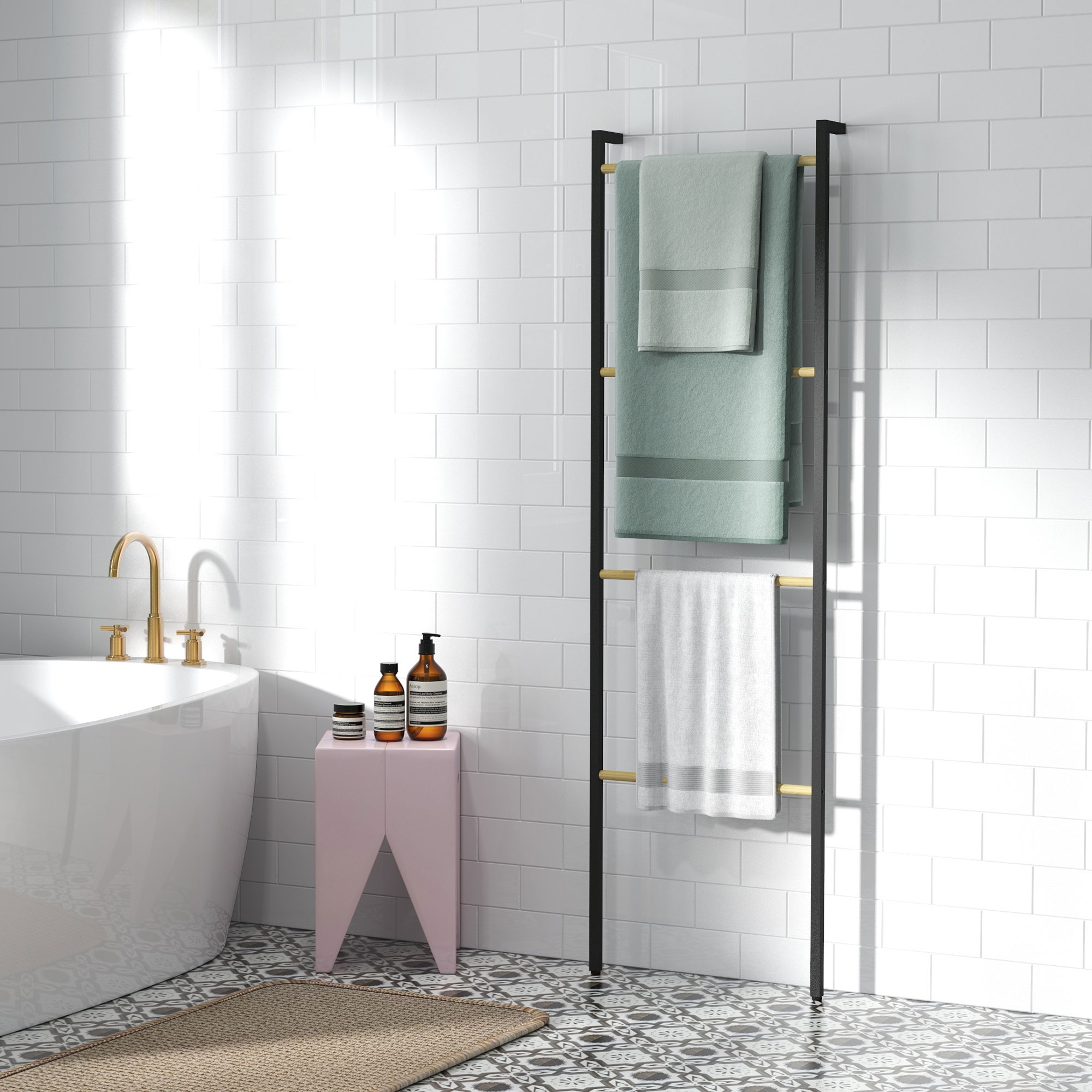 Baño con bañera blanca, toallero negro con toallas verdes y blancas, taburete rosa y suelo de baldosas estampadas.