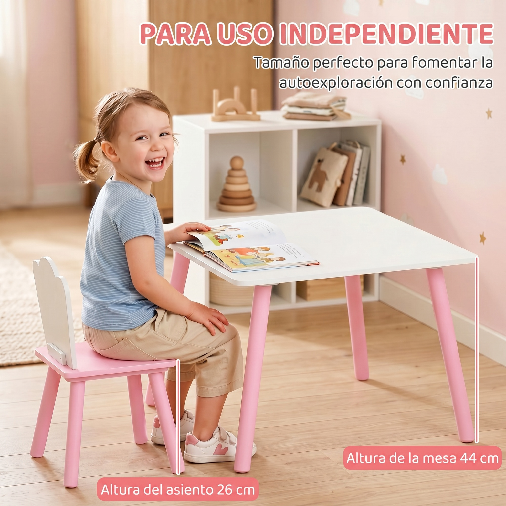 Niño feliz sentado en una mesa infantil blanca y rosa leyendo un libro.
