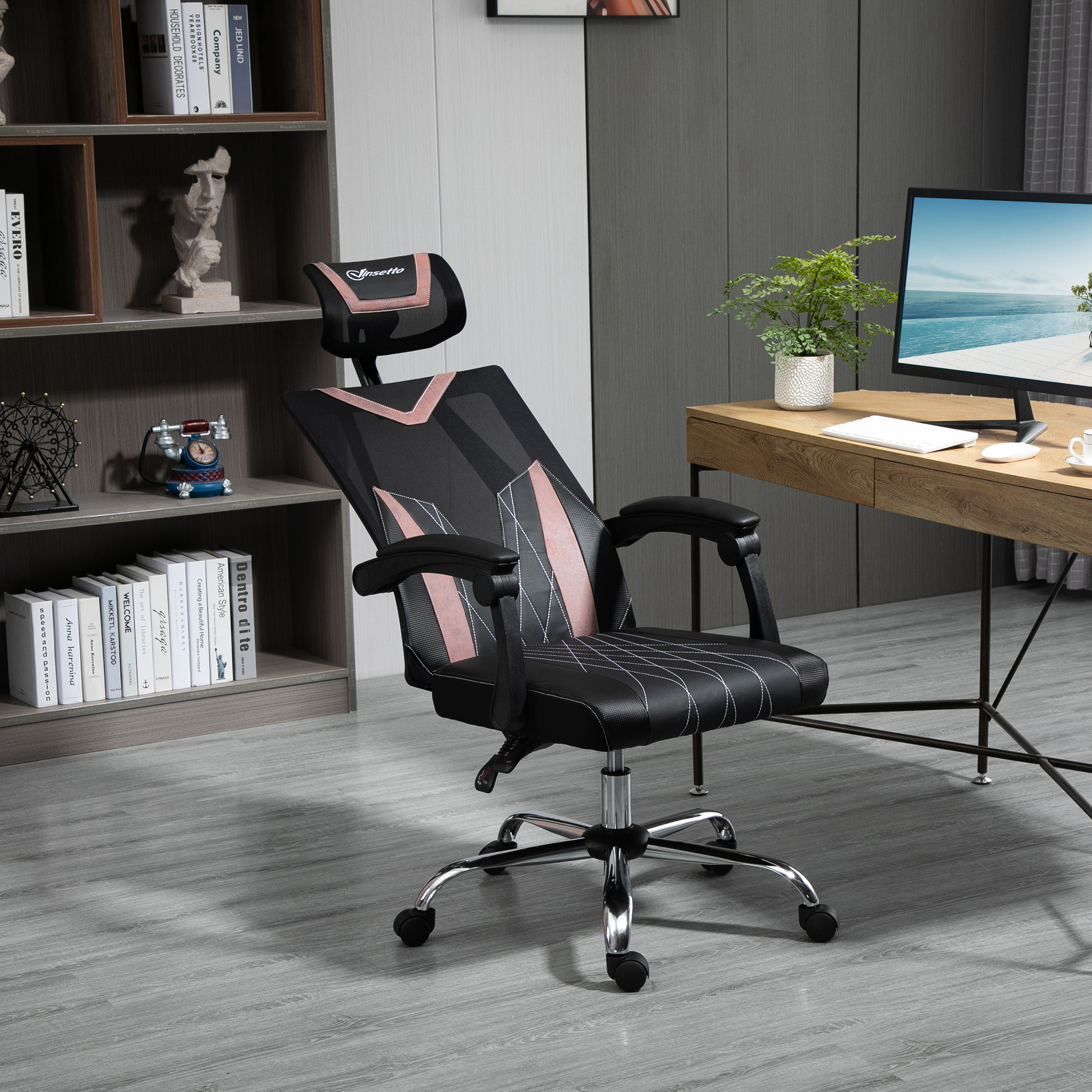 Una sedia da ufficio nera con dettagli rosa in uno studio moderno con scrivania in legno e libreria.