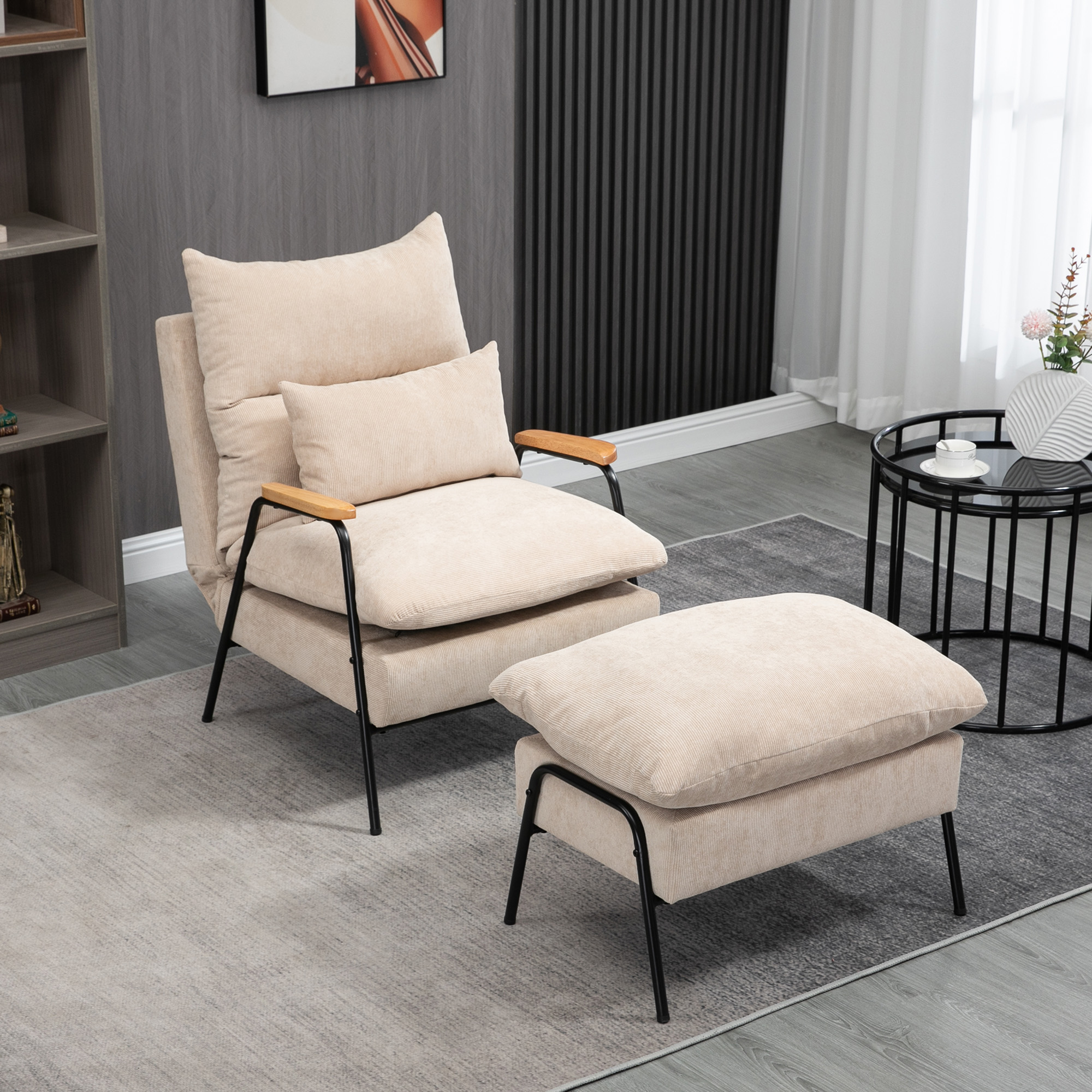 Un sillón beige con su reposapiés en una alfombra gris, junto a una pequeña mesa negra.