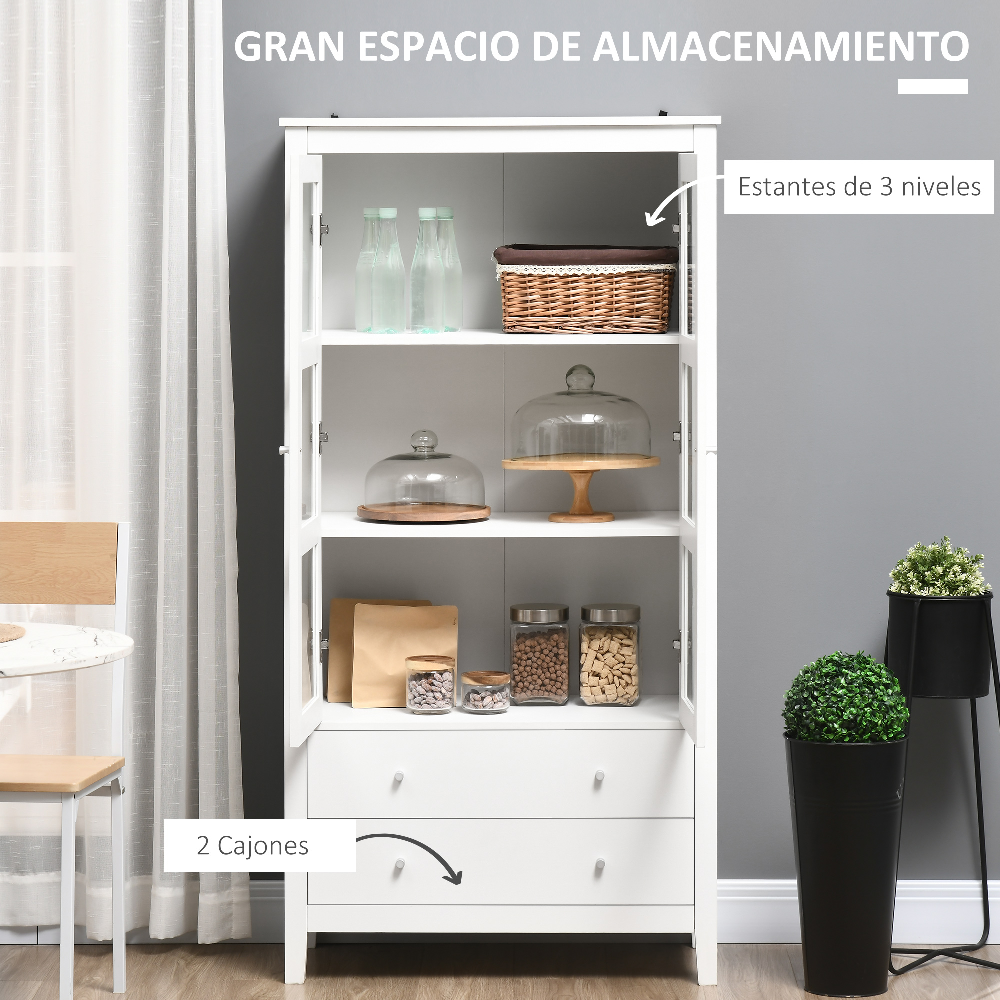 Un armario de madera blanca con puertas de cristal, tres estantes con tarros y cestas, y dos cajones abajo.