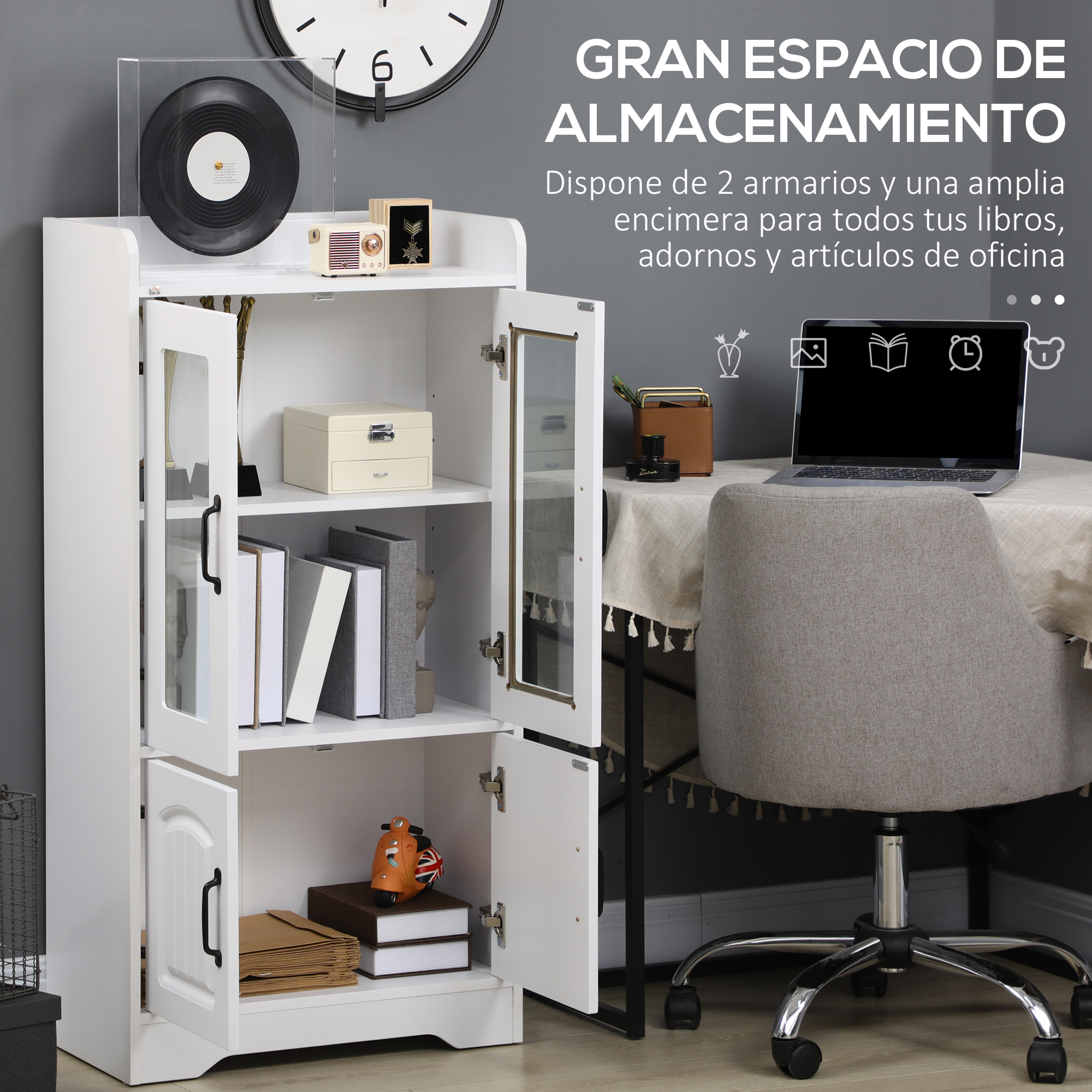 Un armario blanco con puertas de cristal junto a un escritorio con portátil y silla gris.