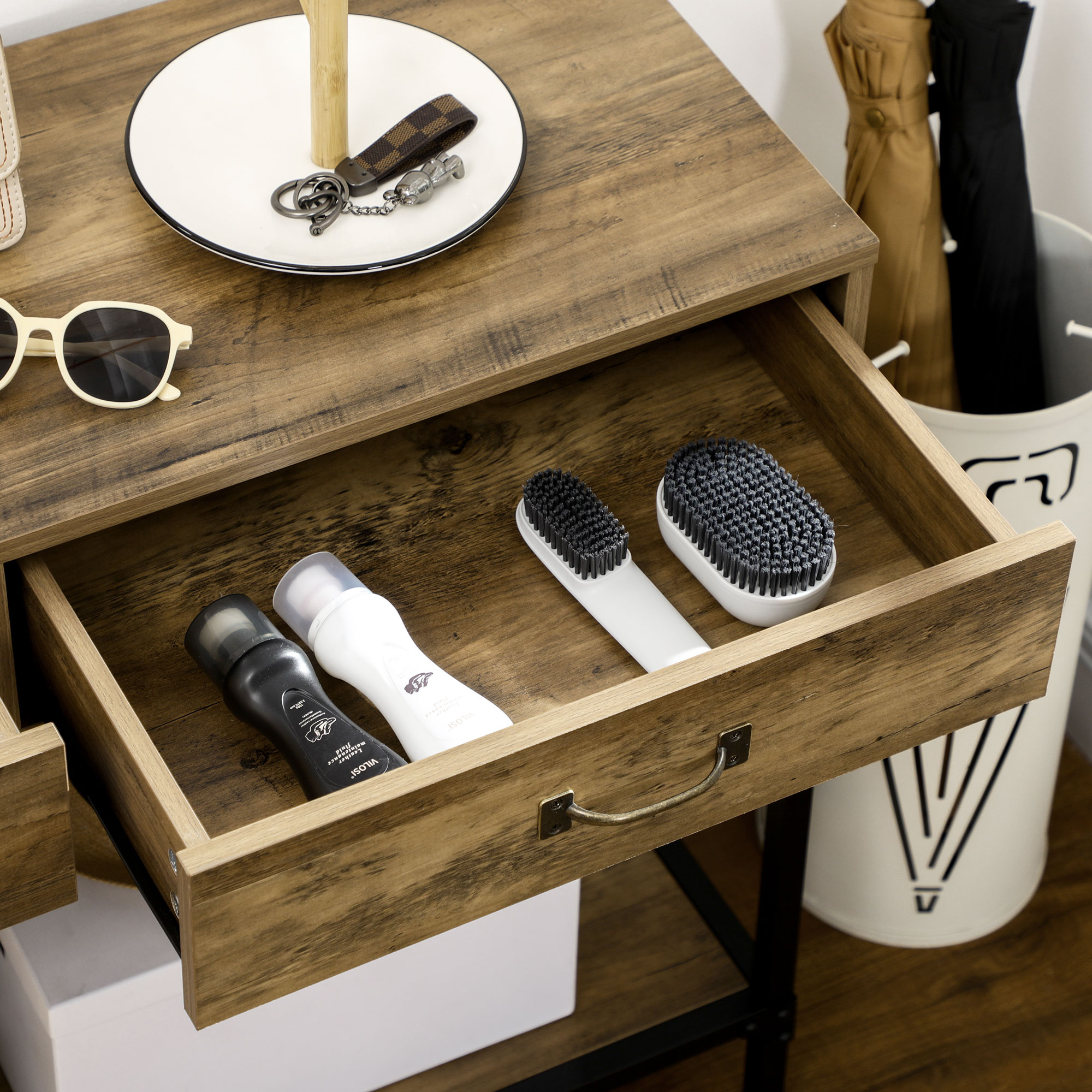 Un cajón abierto de una mesa de madera muestra cepillos y botellas, con gafas de sol y una bandeja en la mesa.