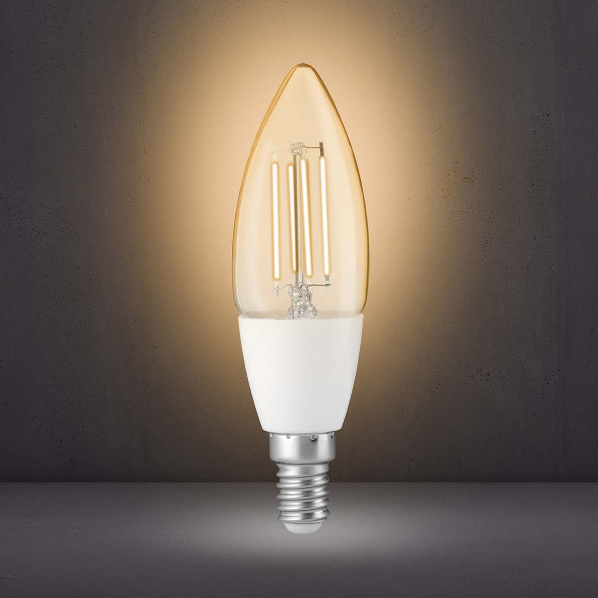 Eine brennende LED-Kerzenlampe mit sichtbaren Filamenten leuchtet vor einem grauen Hintergrund.