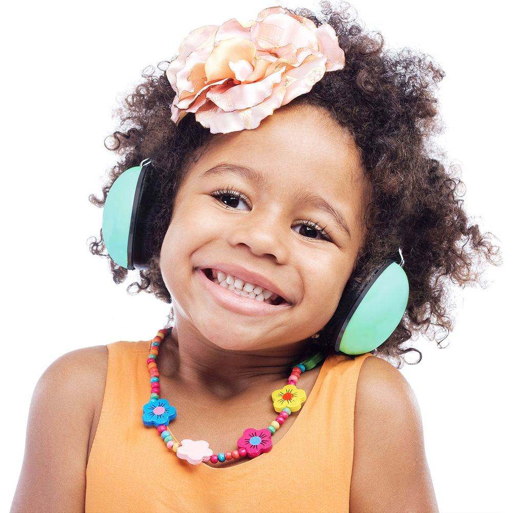 Ein smiling Mädchen mit Afro-Haaren trägt grüne Ohrschützer, eine große rosa Blume und eine bunte Perlenkette.