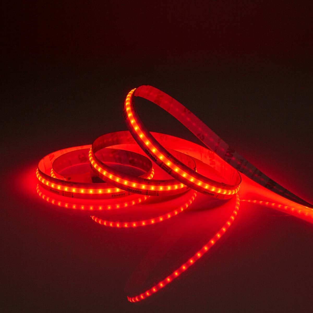 Coiled LED light strip glowing brightly in red in a dark room.