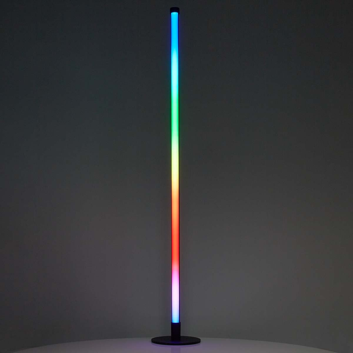 Un lampadaire élancé doté d'un dégradé de couleurs RGB vertical brille dans une pièce sombre.