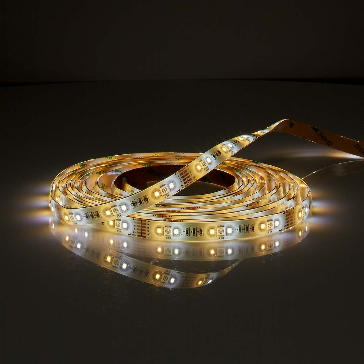 Una striscia LED arrotolata brilla su una superficie scura e riflettente.