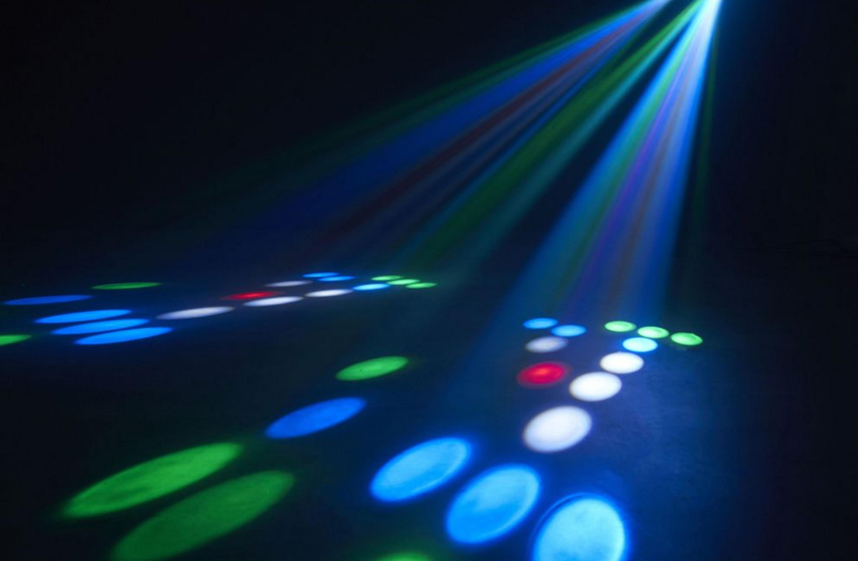 Bunte Lichtstrahlen scheinen von oben herab und erzeugen blaue, grüne und rote Flecken auf dem Boden.