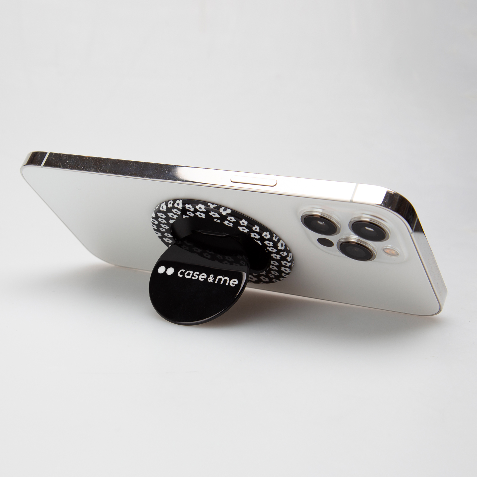 Un teléfono blanco con soporte estampado en blanco y negro y texto case & me sobre fondo blanco.