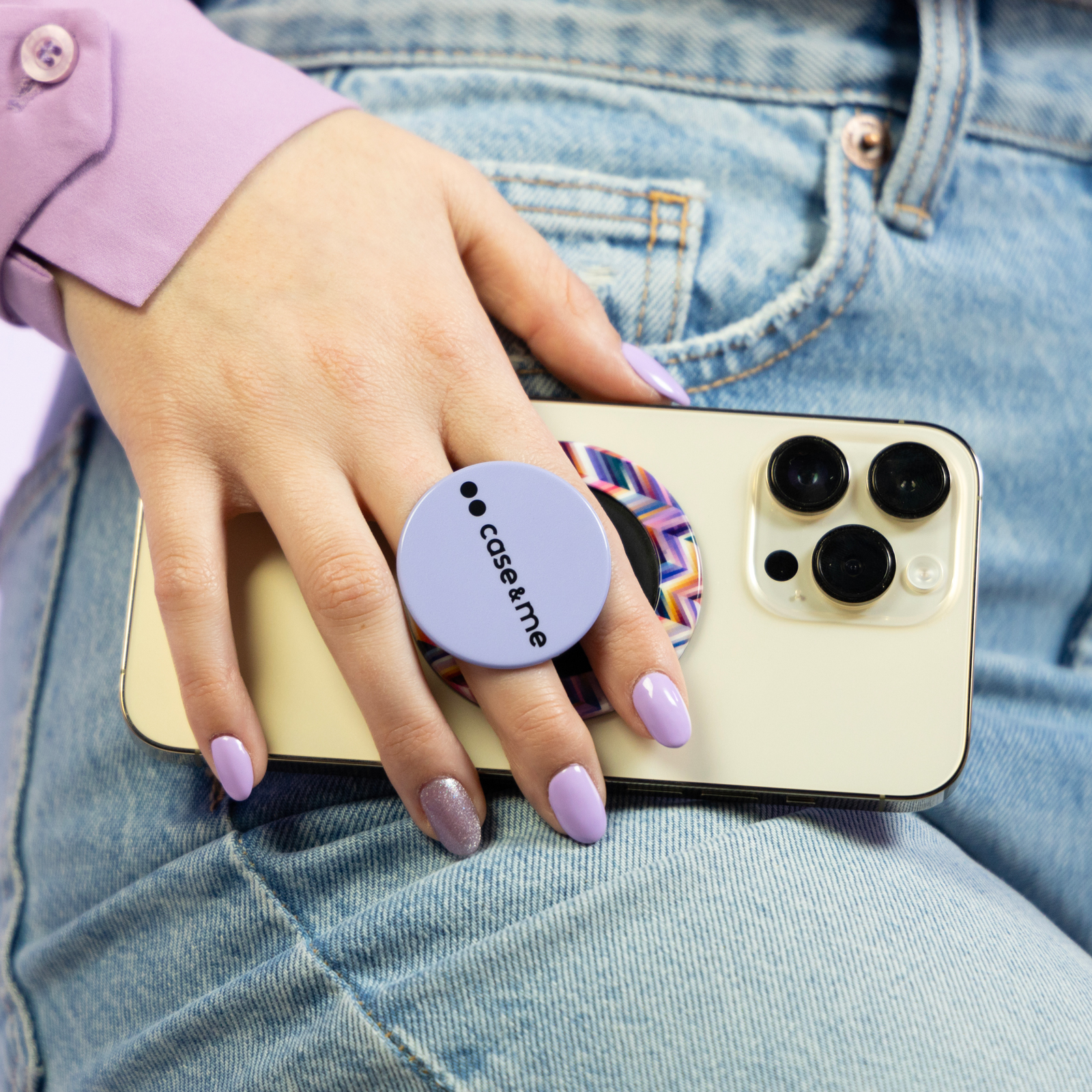 Mano con esmalte de uñas morado sostiene un smartphone con soporte en vaqueros.